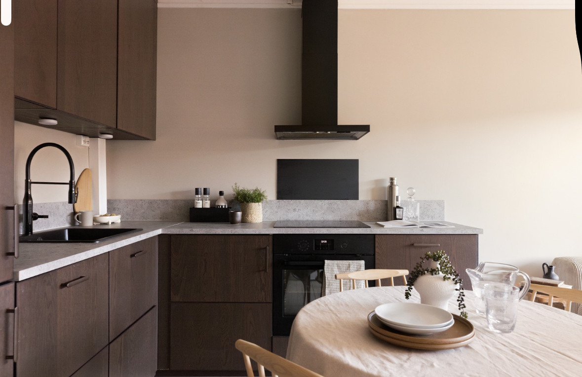 Kjøkkenet har glatte brunbeisede fronter, en dekorativ benkeplate med nedfelt svart kum av kompositt, samt glassplate over stekeovn for enkel rengjøring.