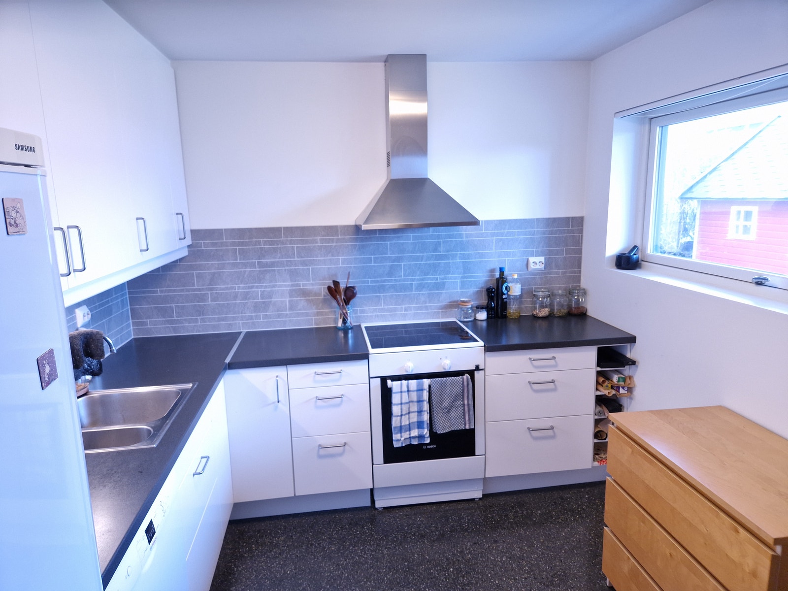 Lyst og romslig kjøkken med hvitevarer.