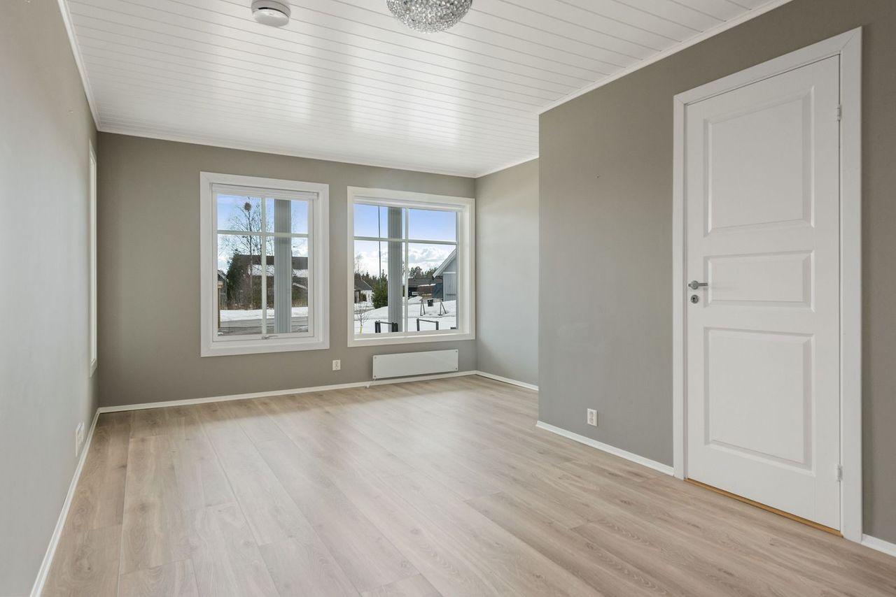 Romslig stue med store vinduer. Høyt under taket