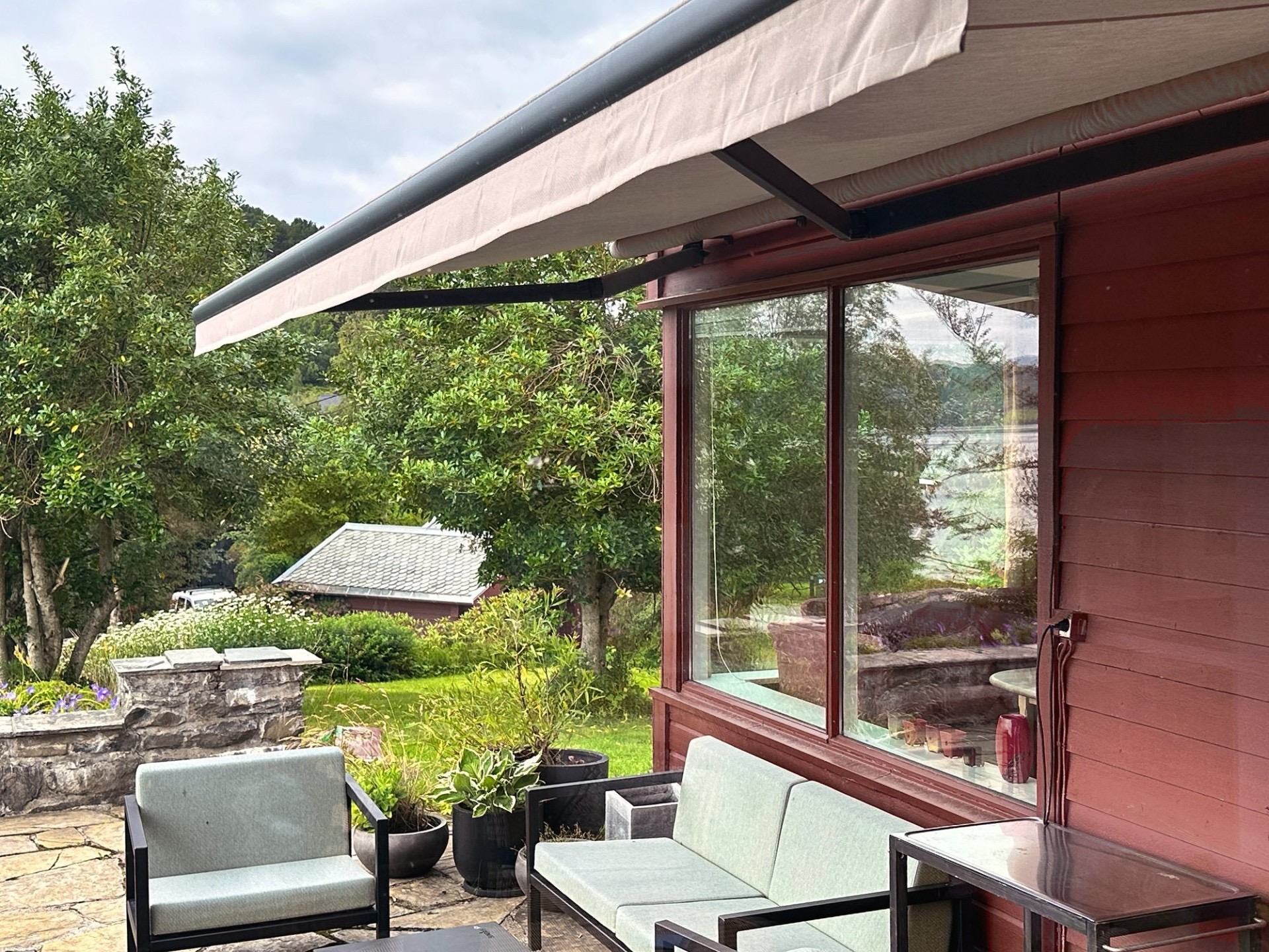 Stenlagt terrasse. Markise. Utgang fra hagestue