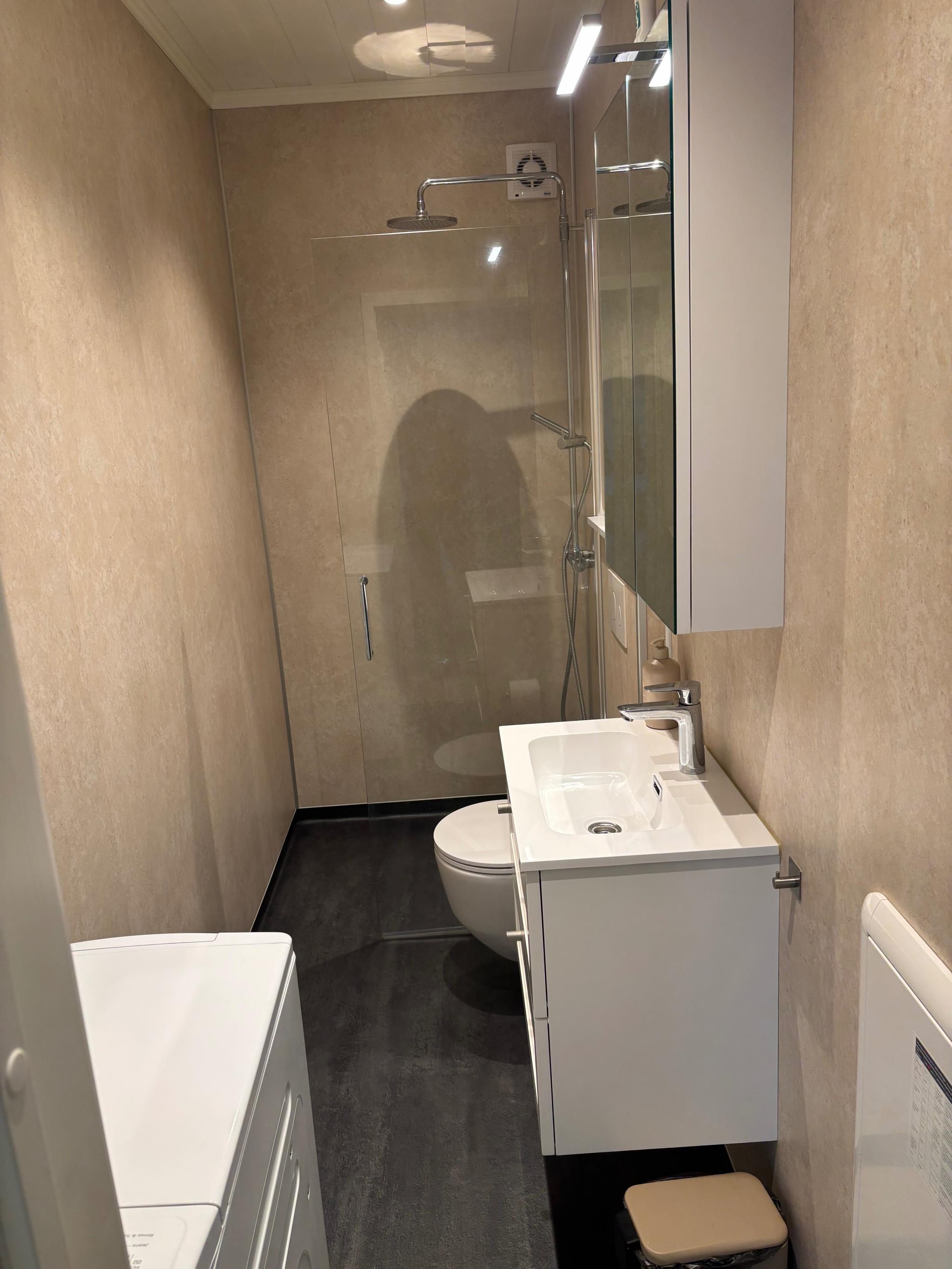 Nytt bad med dusj og vegghengt toalett, vask med to skuffer under og speilskap over, samt ny toppmatet vaskemaskin