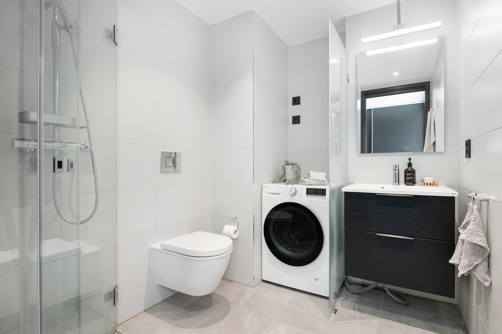 Pent, helfliset bad med varmekabler i gulv, downlights i himling og opplegg for vaskemaskin. Dusjhjørne med innfellbare glassdører, regnfallsdusj og mosaikkfliser på gulv.