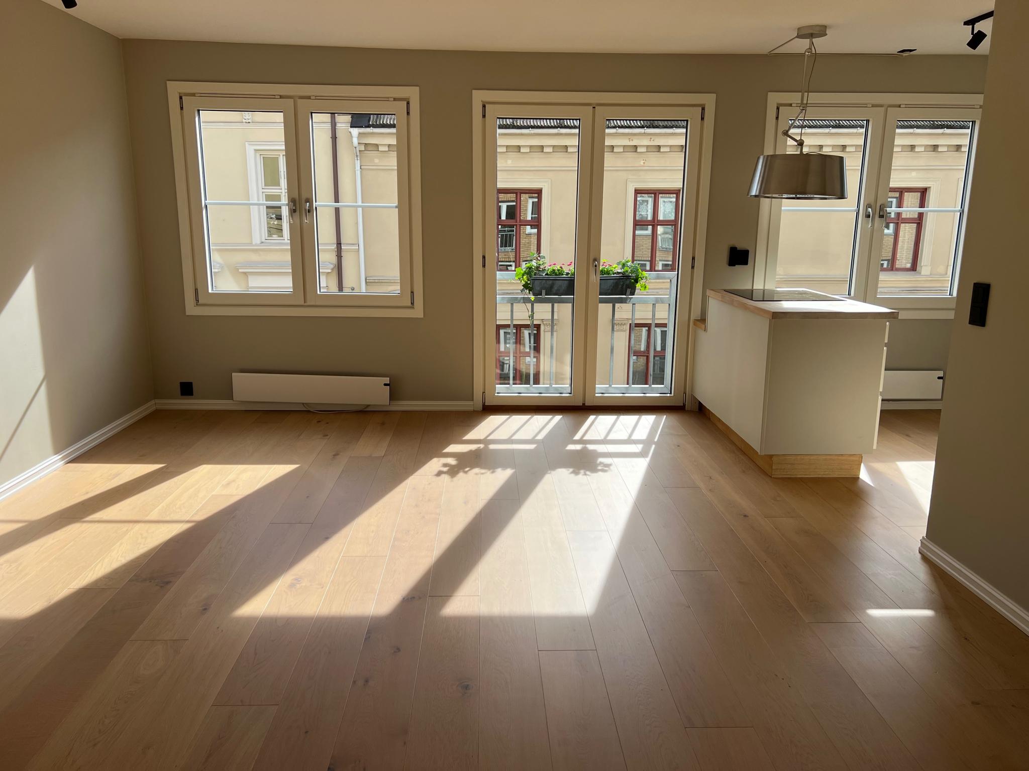 Romslig og lys stue med åpen kjøkkenløsning med plass til både 4-seters sofa og spisebord 