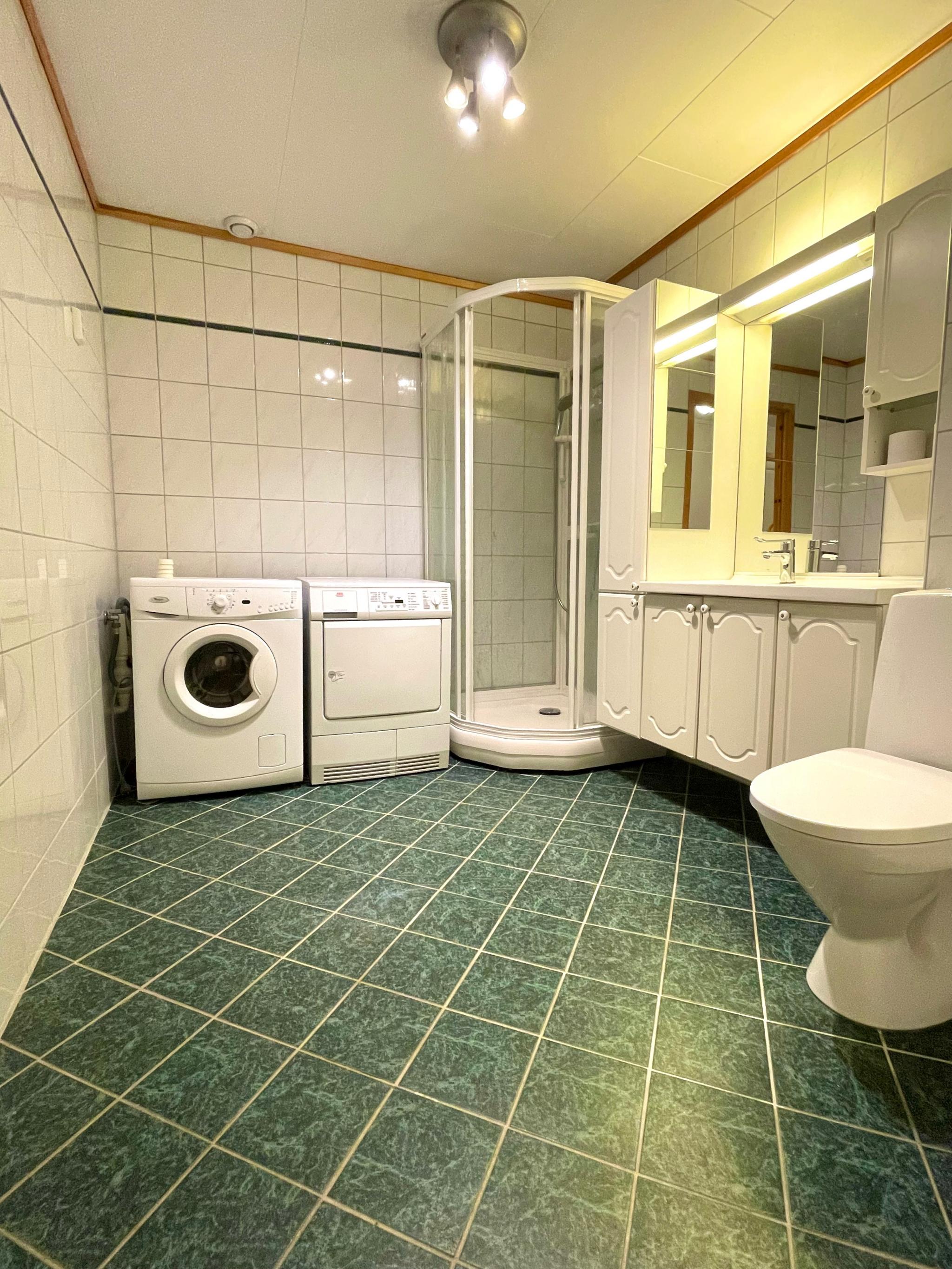 Bad med dusj kabinett, varmekabler, vaskemaskin og tørketrommel.