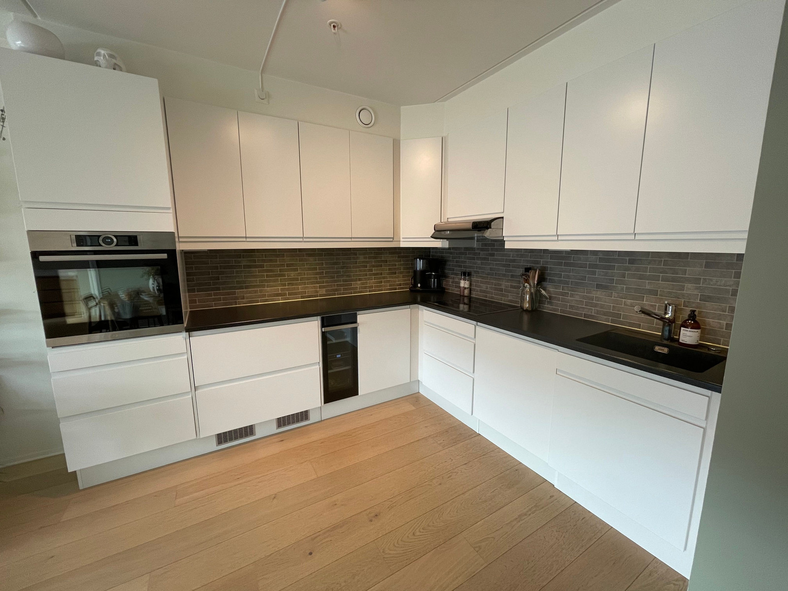 Åpen løsning mot kjøkken med integrerte hvitevarer og vinkjøler