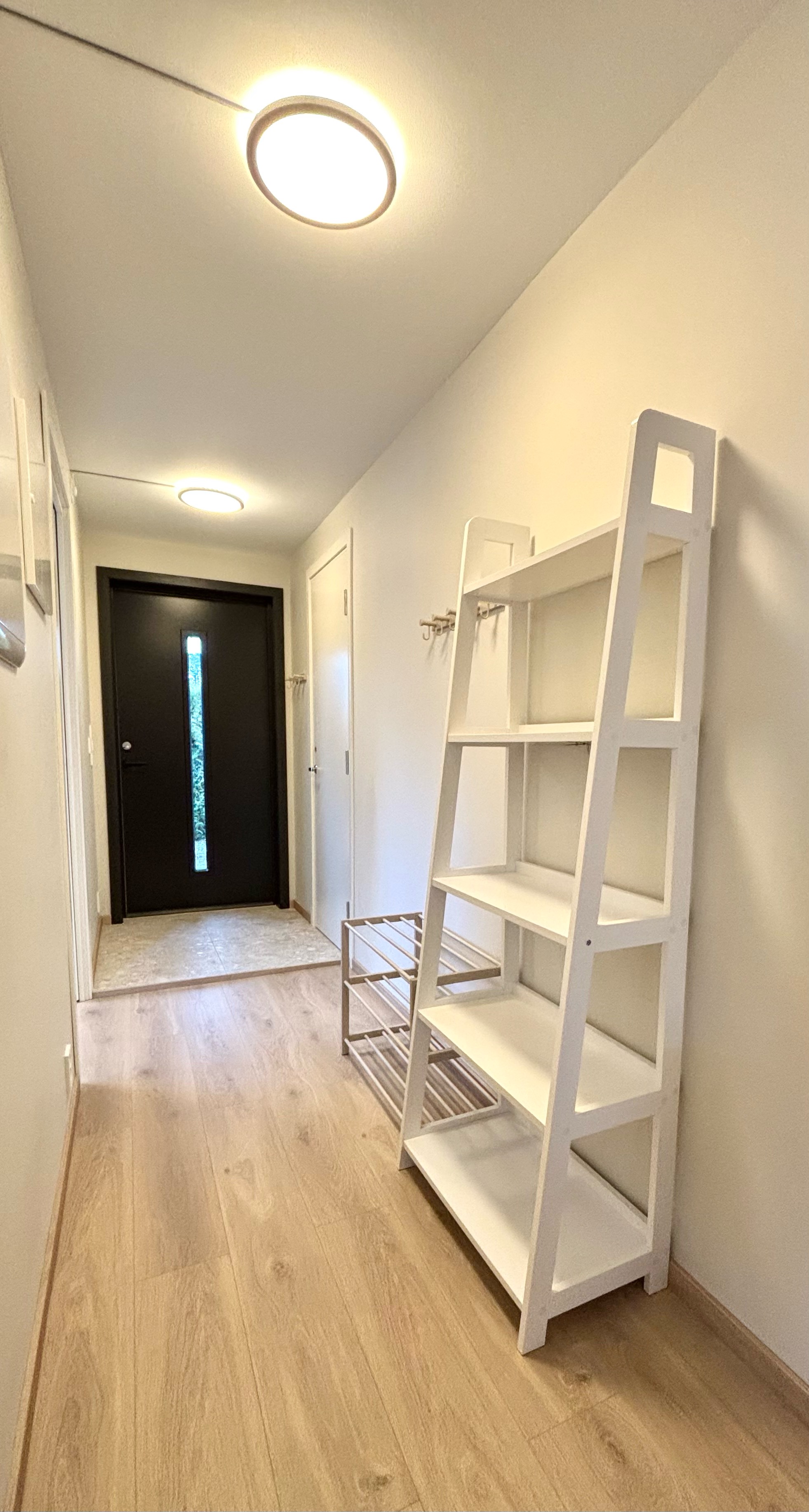 Lys gang med knagger og hyller. 