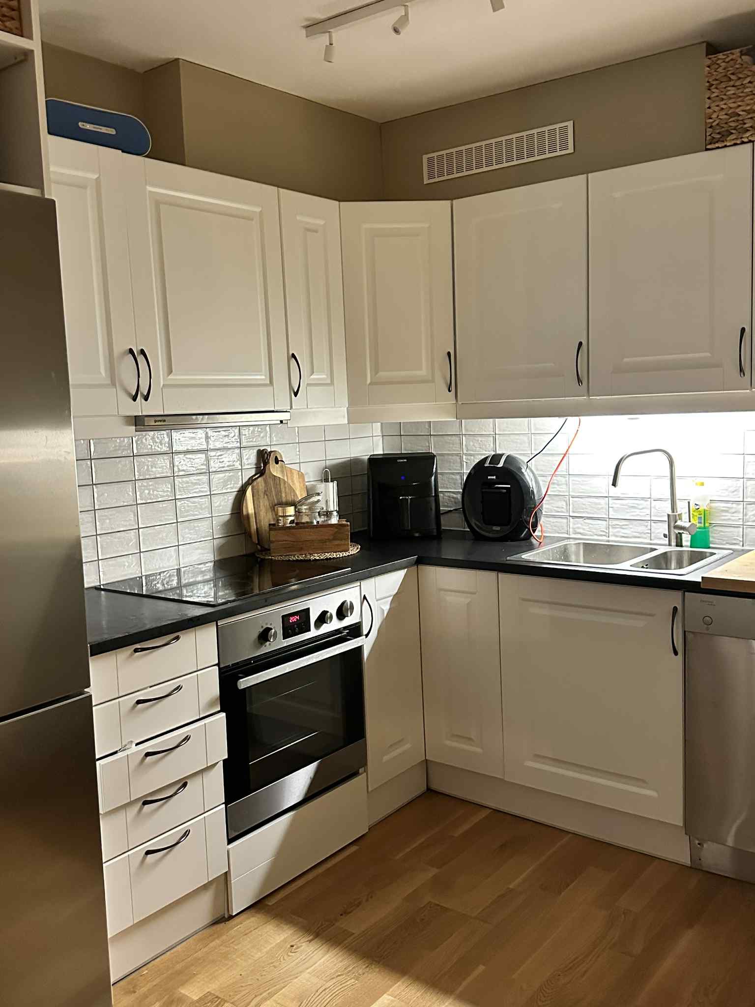 Kjøkkenet med ovn, koketopp, mikrobølgeovn, oppvaskmaskin og kjøleskap.