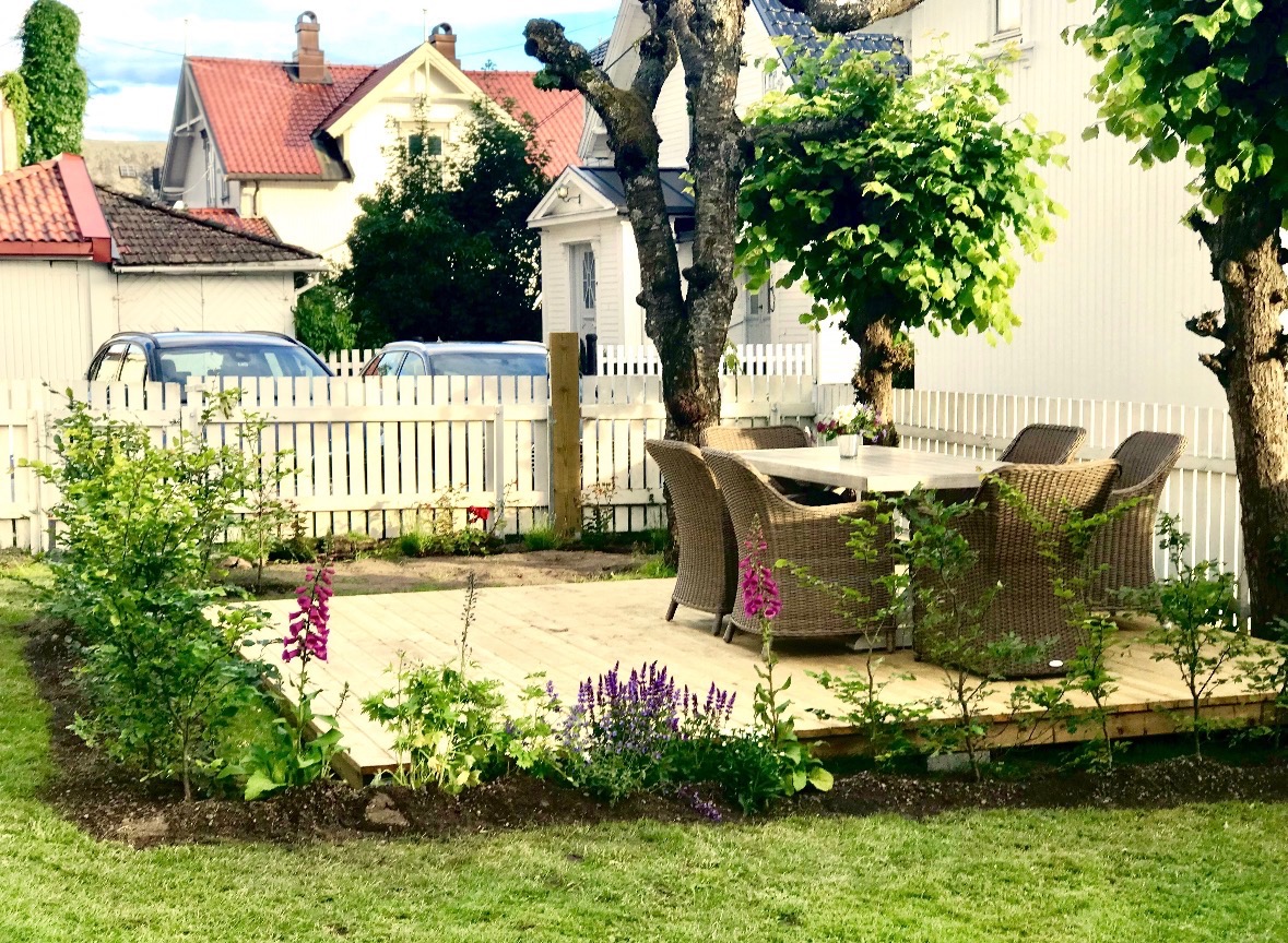 Seksjonert uteområde oppgradert med platting og beplantet med blant annent bøkehekk og roser busker.