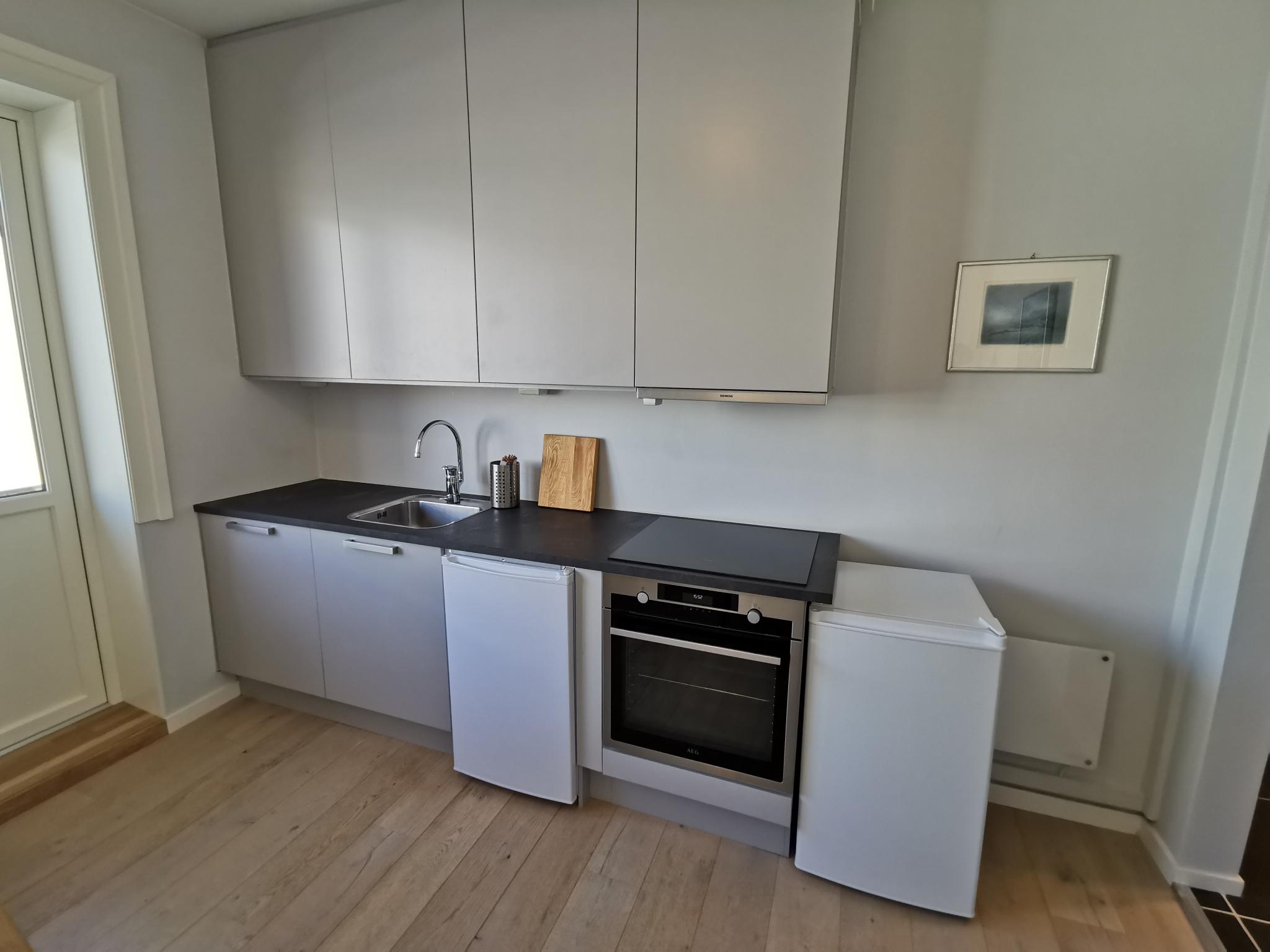 Kjøkken med oppvaskmaskin, kjøleskap og fryser. 