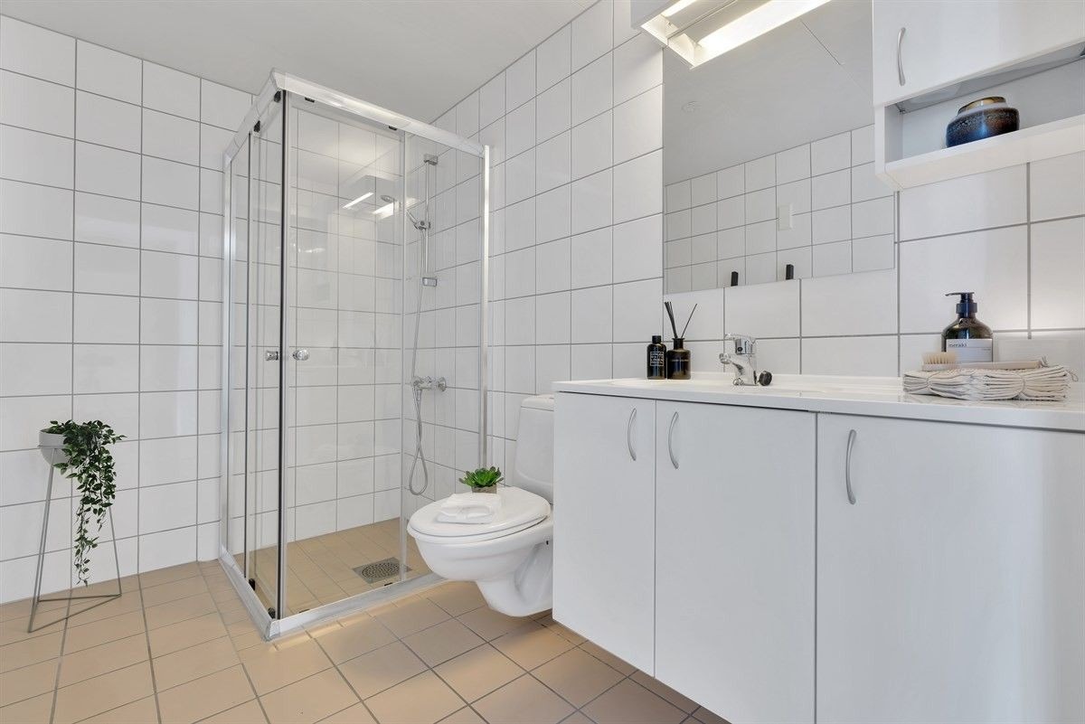 Romslig bad/toalett med vaskemaskin og tørketrommel.