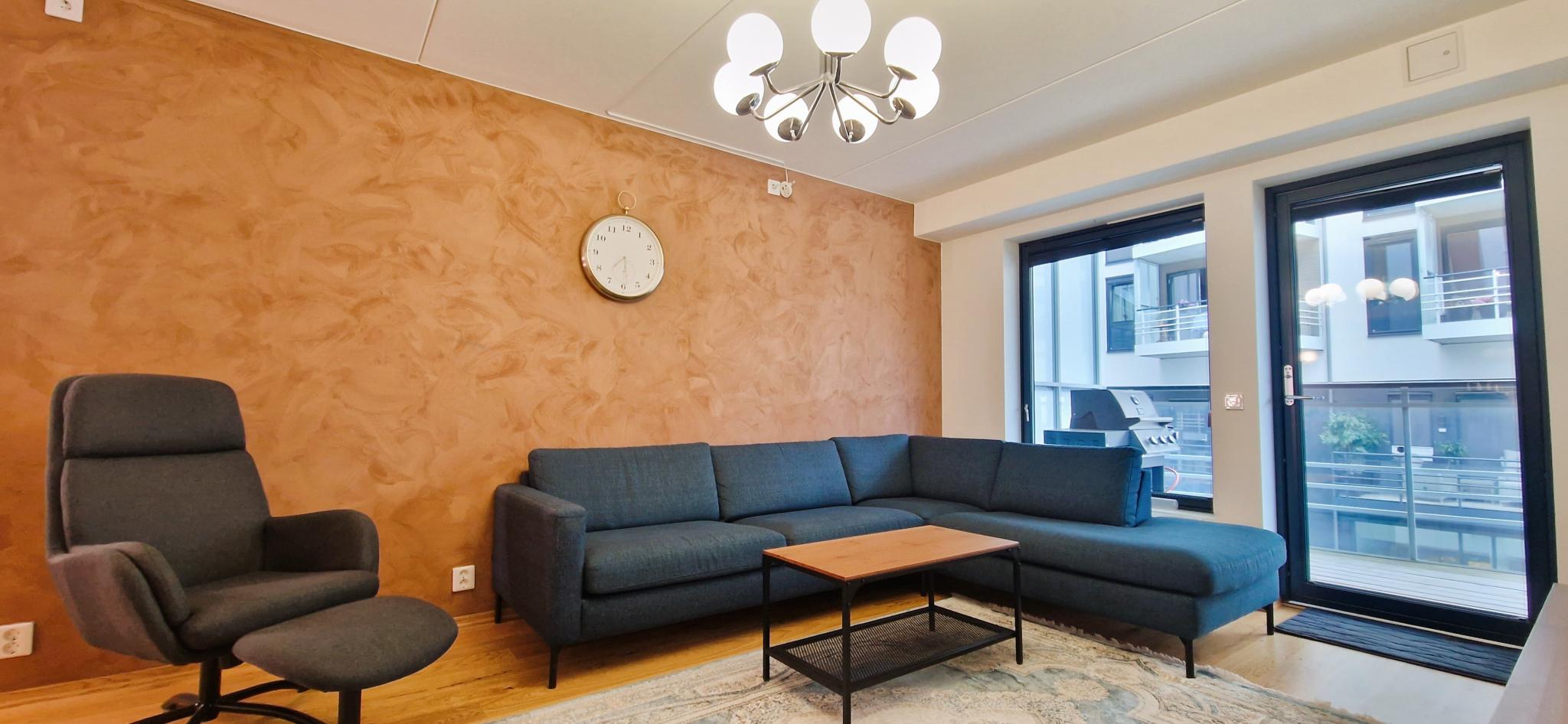 Romslig stue med store vindusflater og inngang til balkong