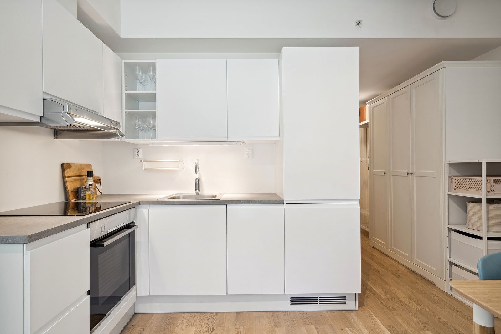 Moderne kjøkken med integrerte hvitevarer. Det er kjøl og fryseskap, komfyr, platetopp, vifte og oppvaskmaskin.