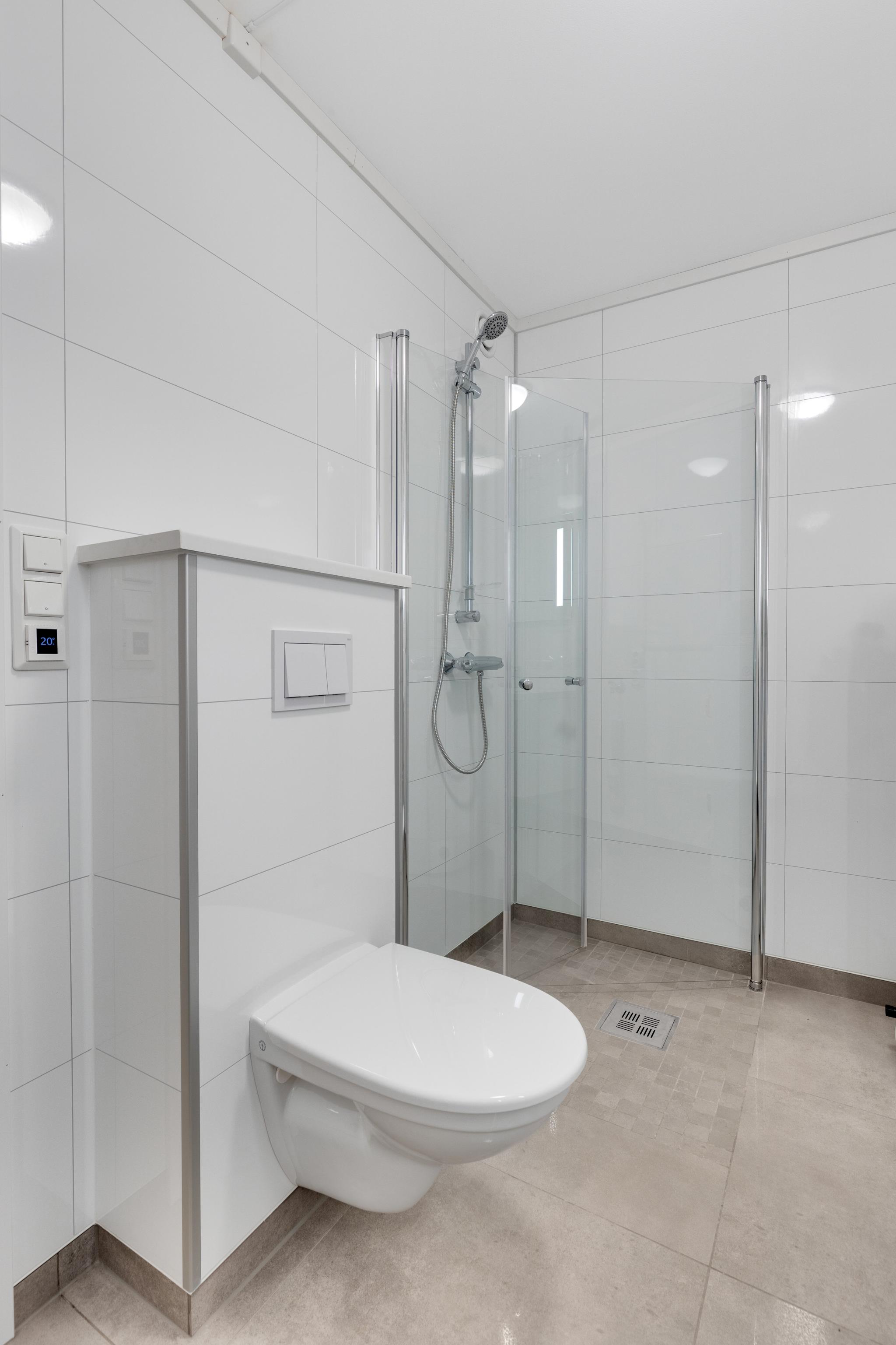 Badet har praktisk planløsning med dusjsone, toalett og opplegg for vaskemaskin.