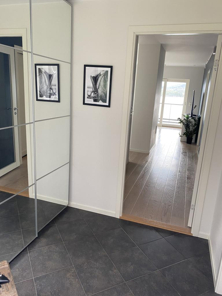 Bilde fra inngangsdør. Flislagt gang med varmekabler, skyvedørsgarderobe medfølger.