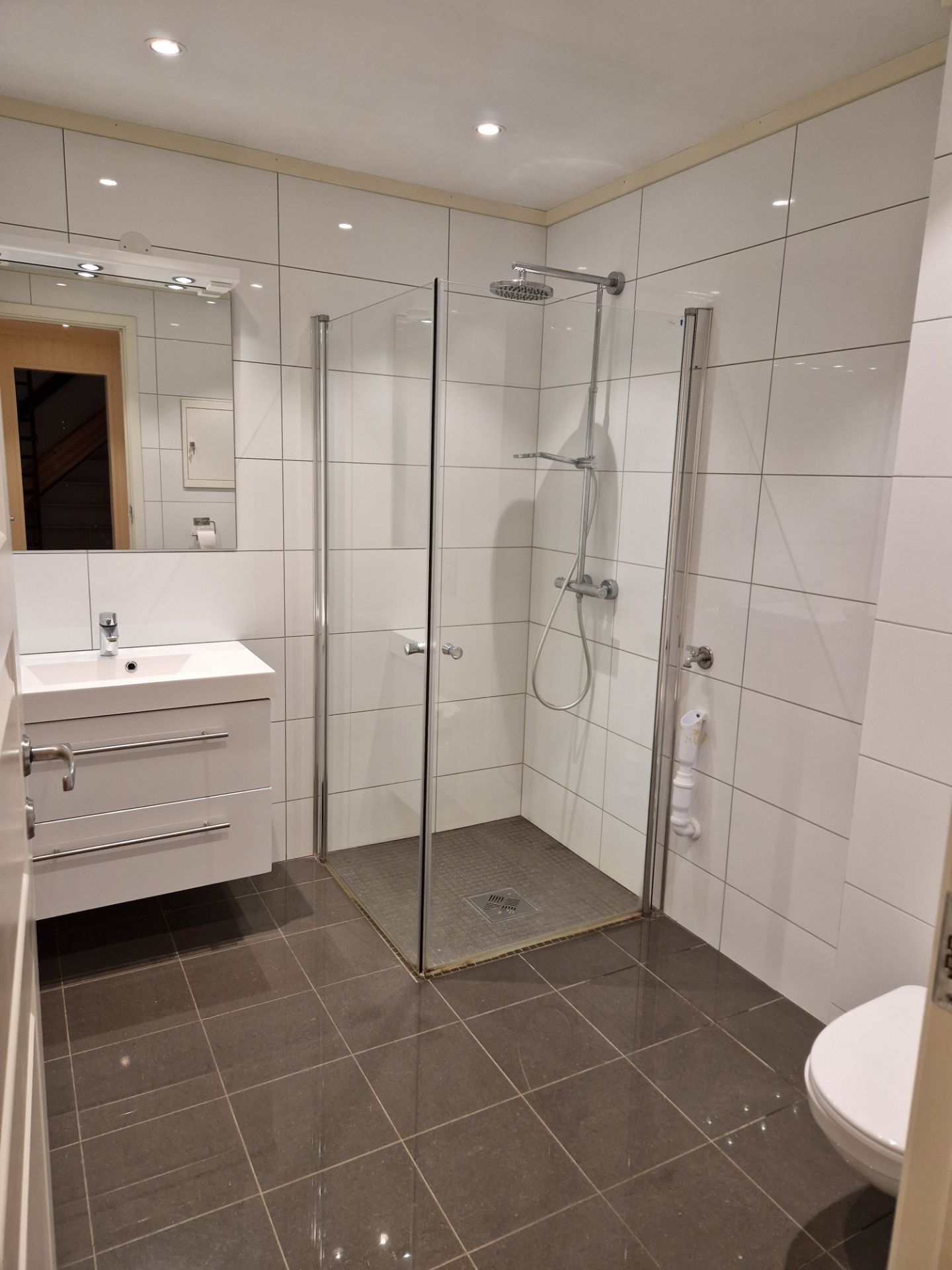 Dusjhjørne, vegghengt toalett, flislagt med varmekabler i gulv og downlights i himling