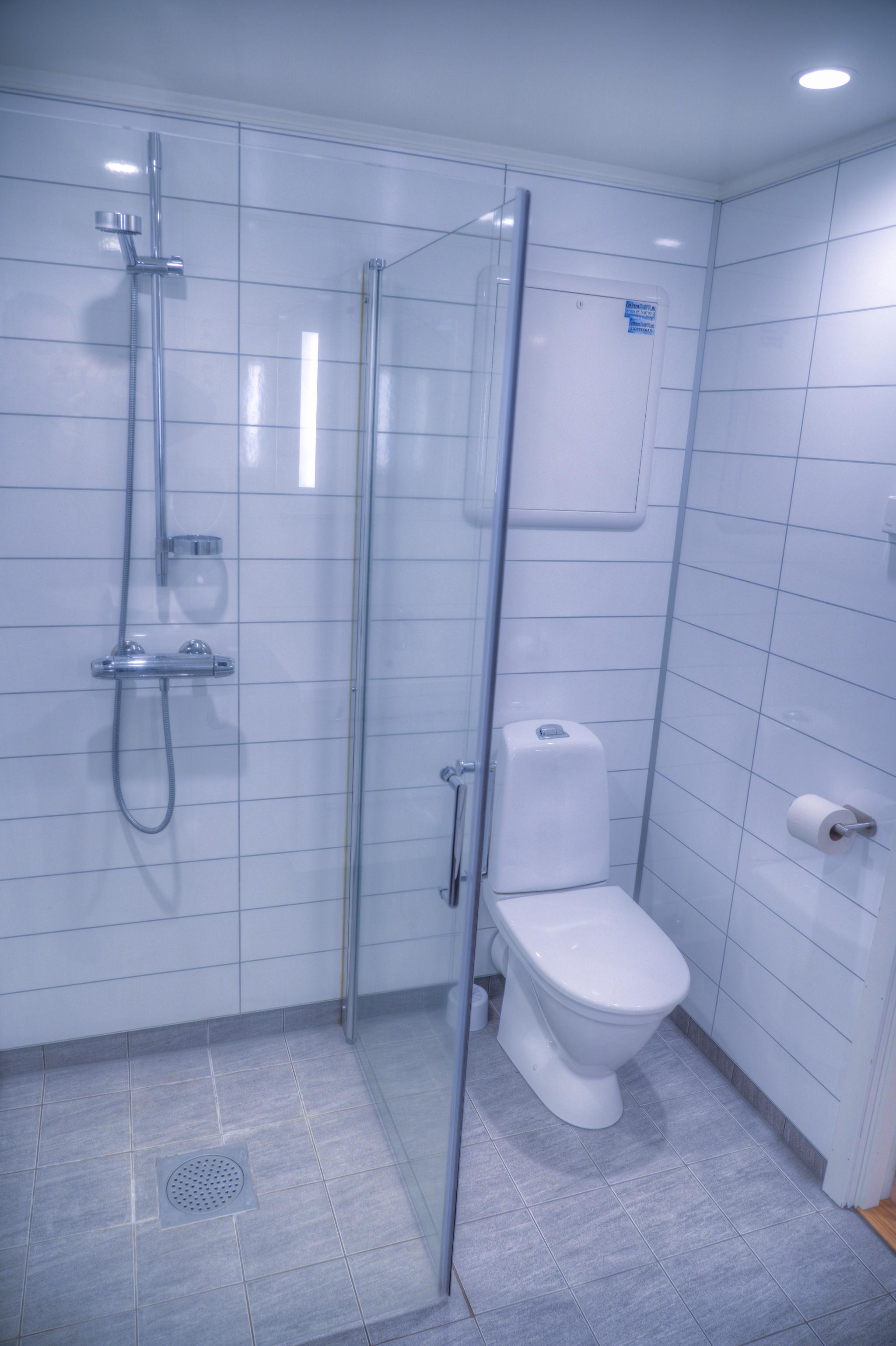 Moderne bad med dusjvegger, fliser på gulv og våtromsplater på vegger.