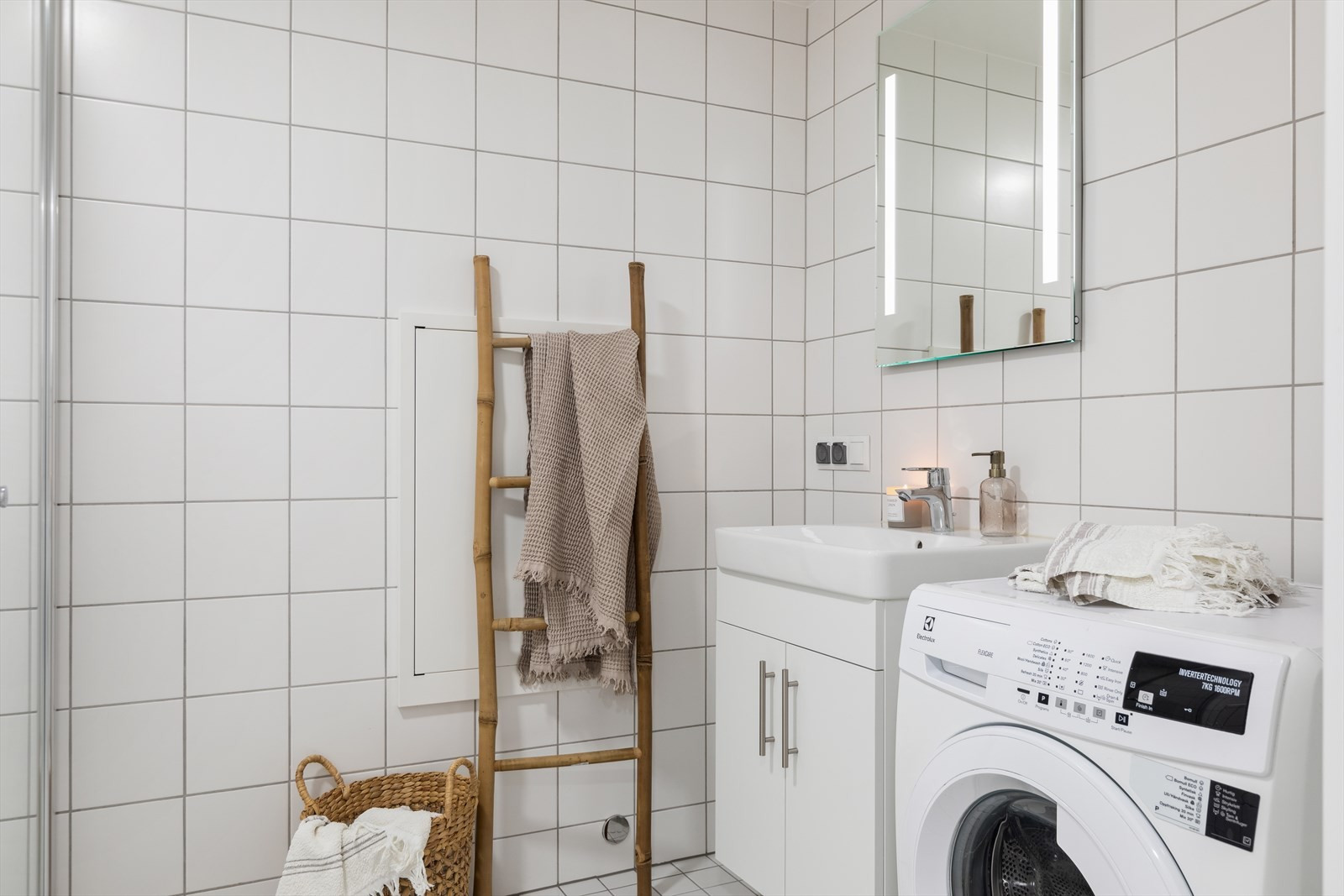 Elegant bad med moderne design preget av rene og hvite fliser. Vaskemaskin følger med.