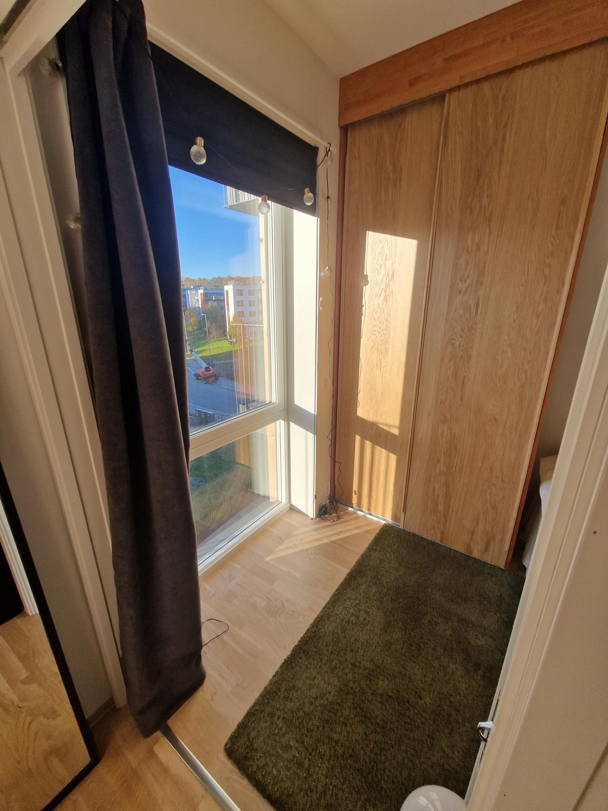 Stort vindu på soverom, med lysdempende plissé og gardin