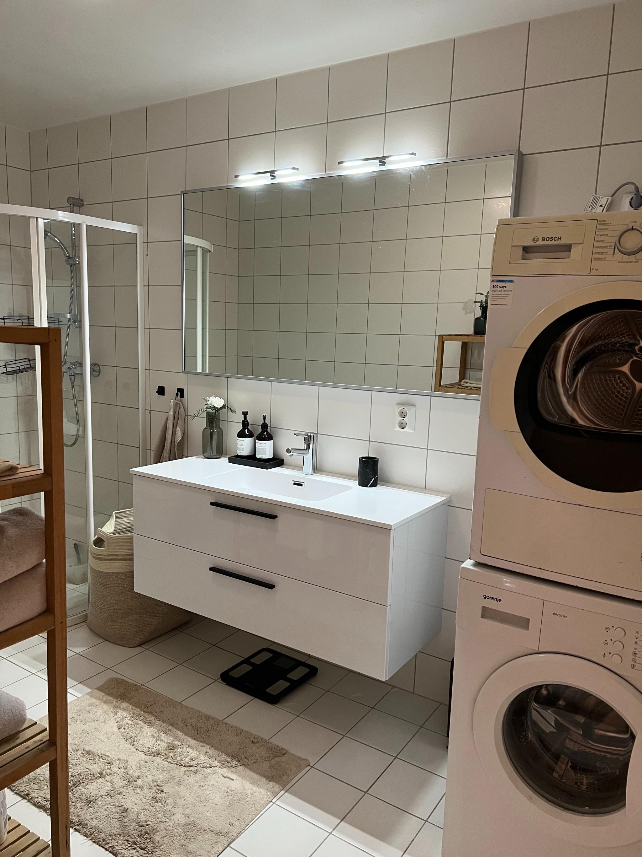 Stor vask og speil på flislagt bad