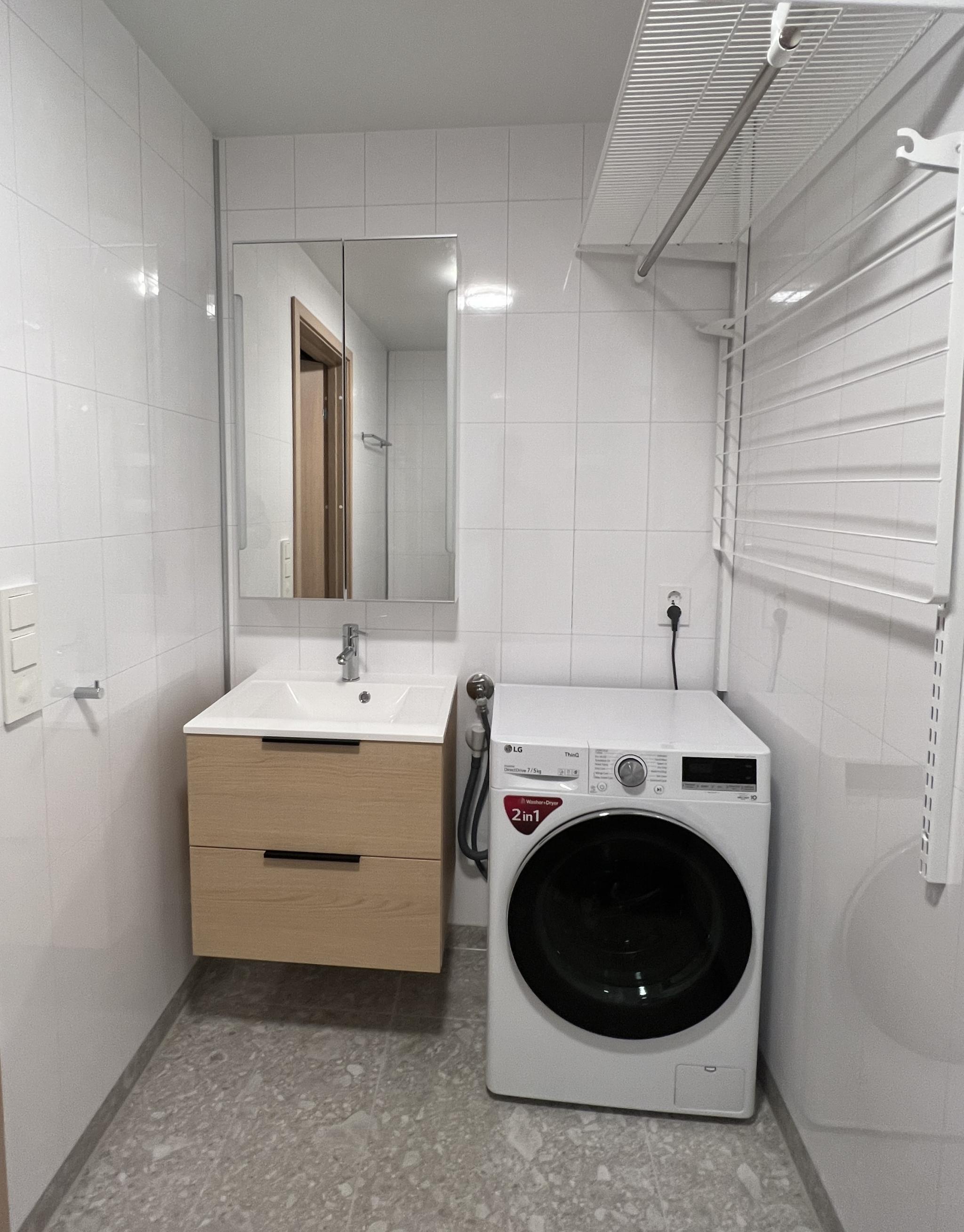 Bad med kombinert vaskemaskin og tørketrommel. Elfa tørkestativ på vegg. 