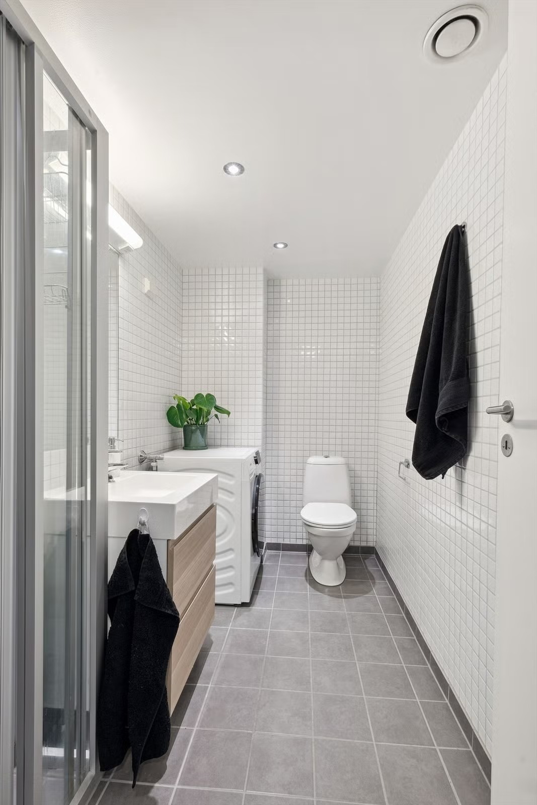 Flislagt baderom med downlights i himlingen.