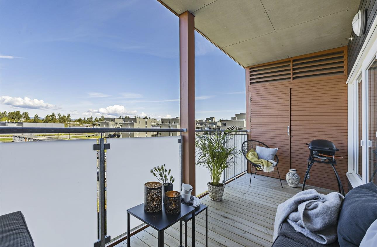 oppbygget balkong med plass til sittegruppe og grill og liten utebod på balkong