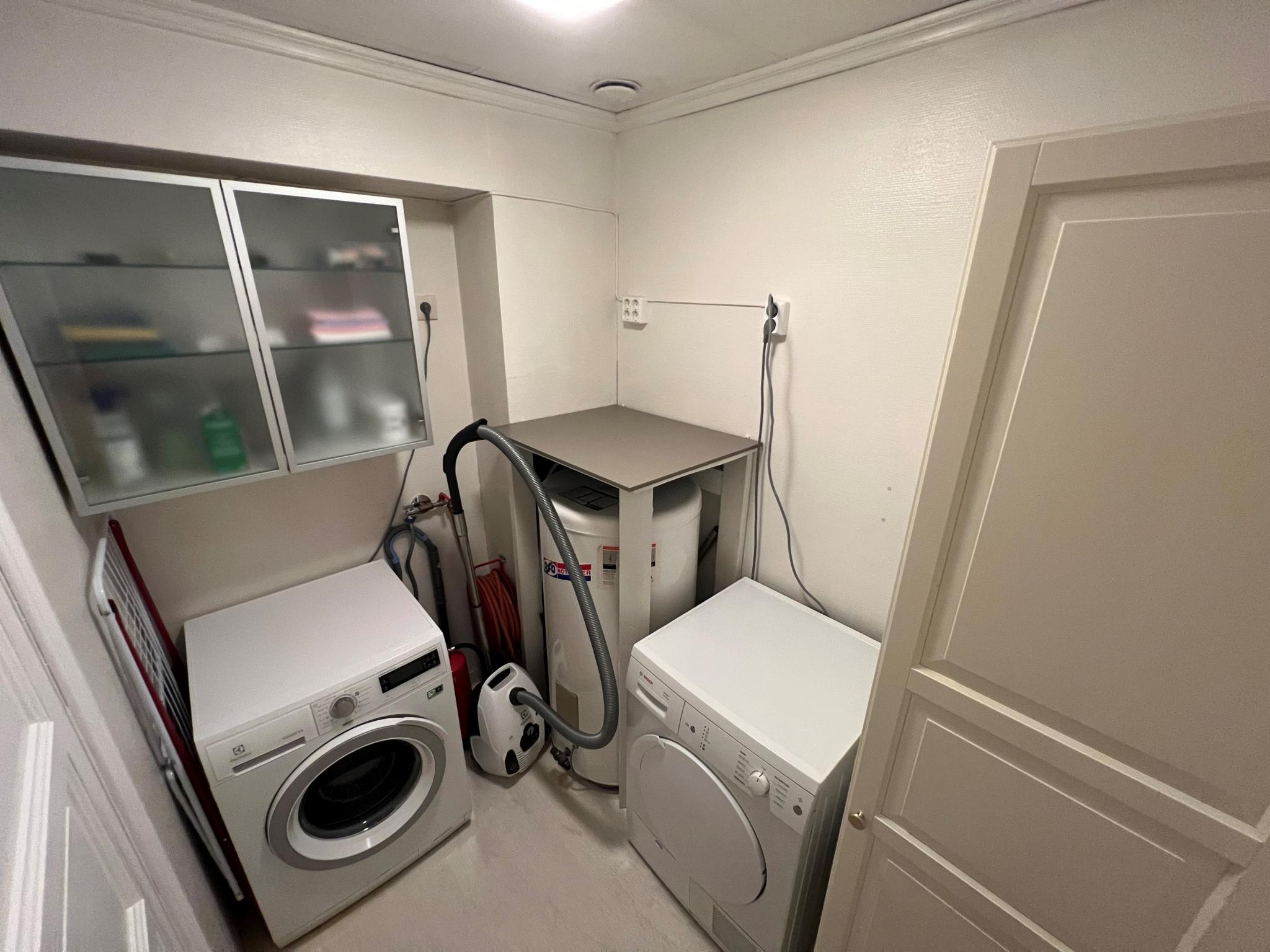 Vaskerom med tørketrommel, vaskemaskin og skap 