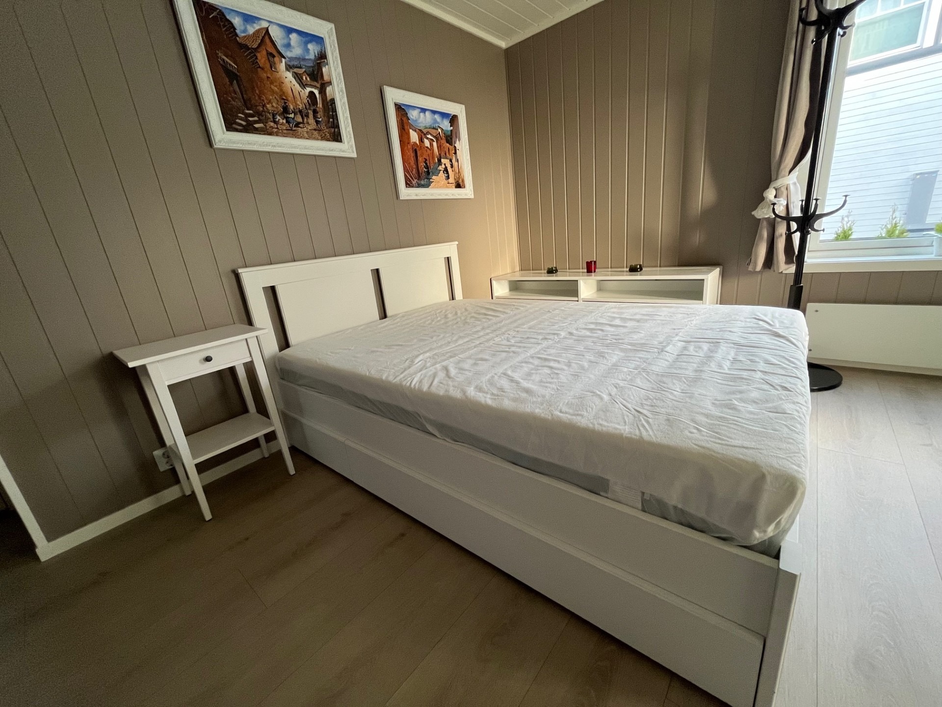 Romslig soverom utstyrt med en 140x200 cm seng, nattbord, kommoder, speil, gardiner, TV-hylle