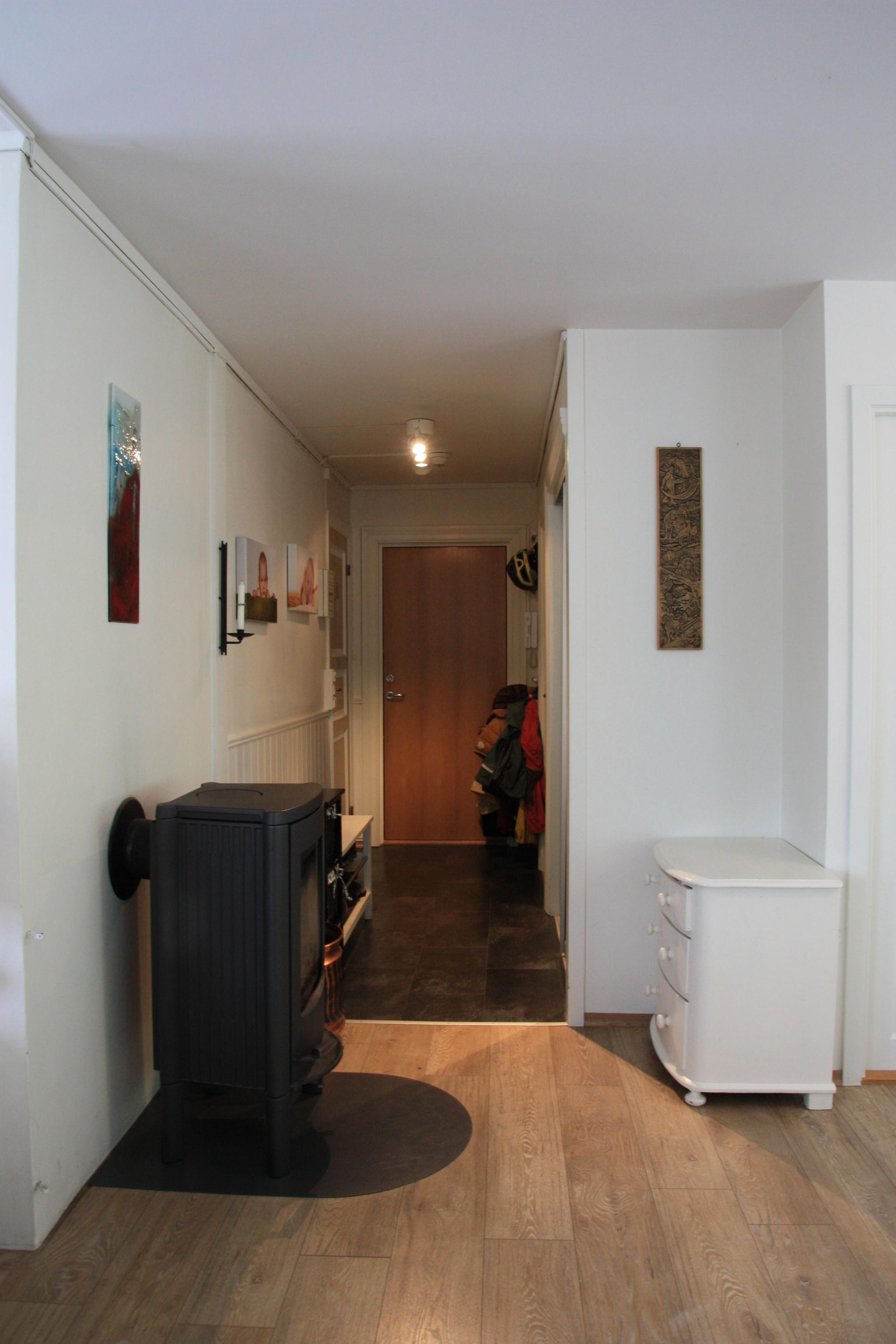 Korridor med romslig skyvedørsgarderobe, skohylle og Peisovn, nærmest stua.