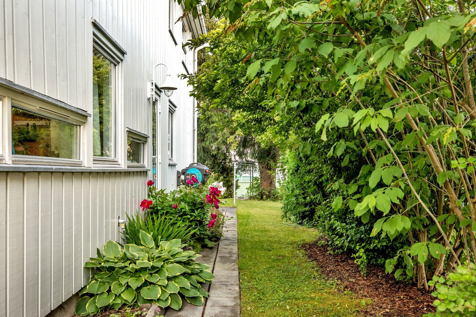 Den herlige hagen byr på beleggningsstein, planter og mange buskevekster.
