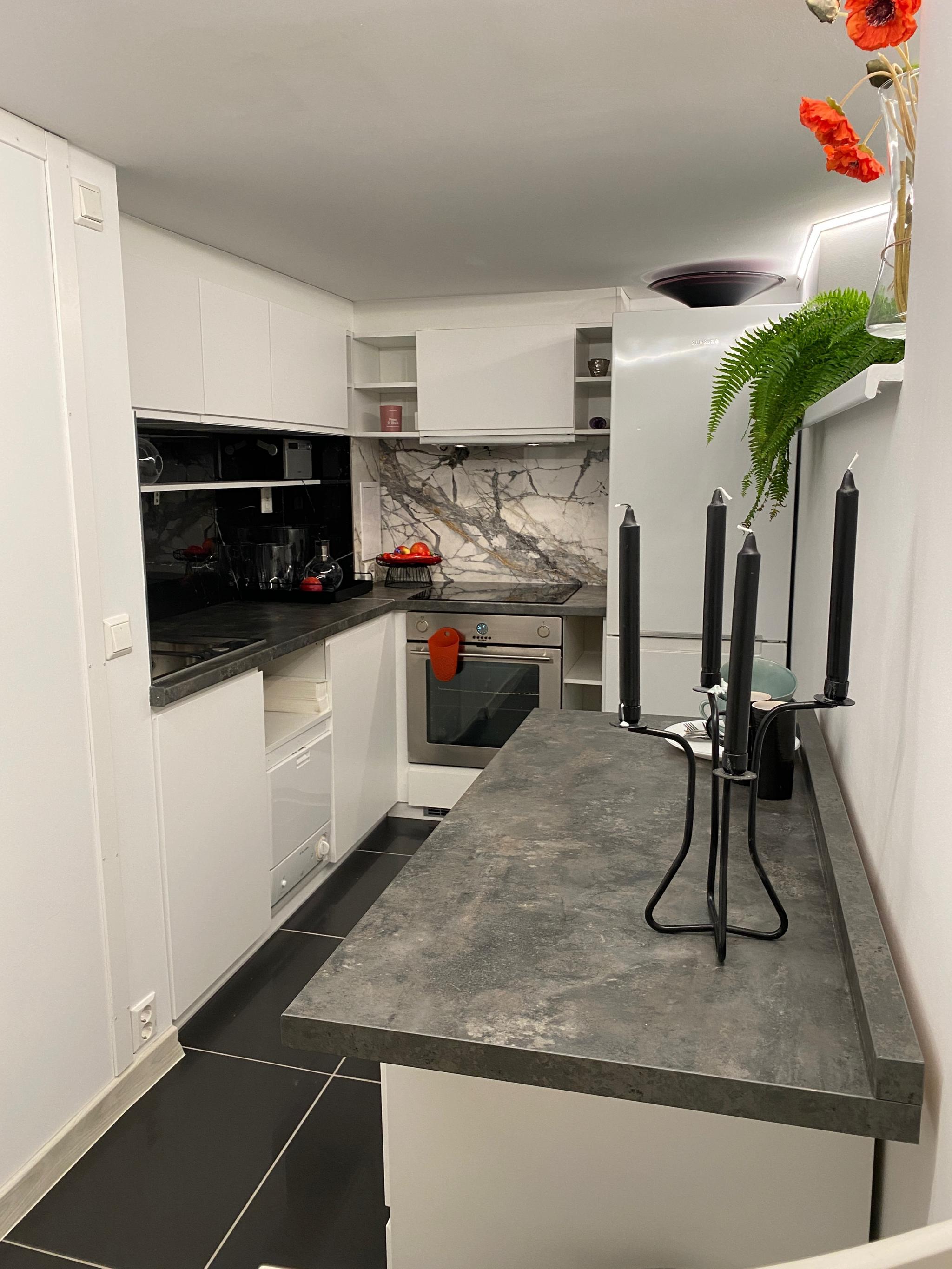 Åpen kjøkkenløsning tilknyttet stue, med komfyr, kjøleskap, mikrobølgeovn og oppvaskmaskin. 