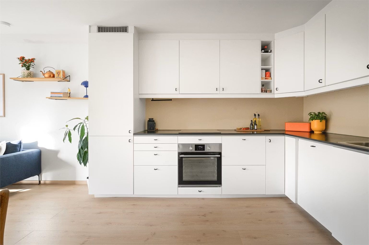 Leiligheten har et romslig kjøkken med god benkeplass. Hvitevarene er sømløst integrert i innredningen.