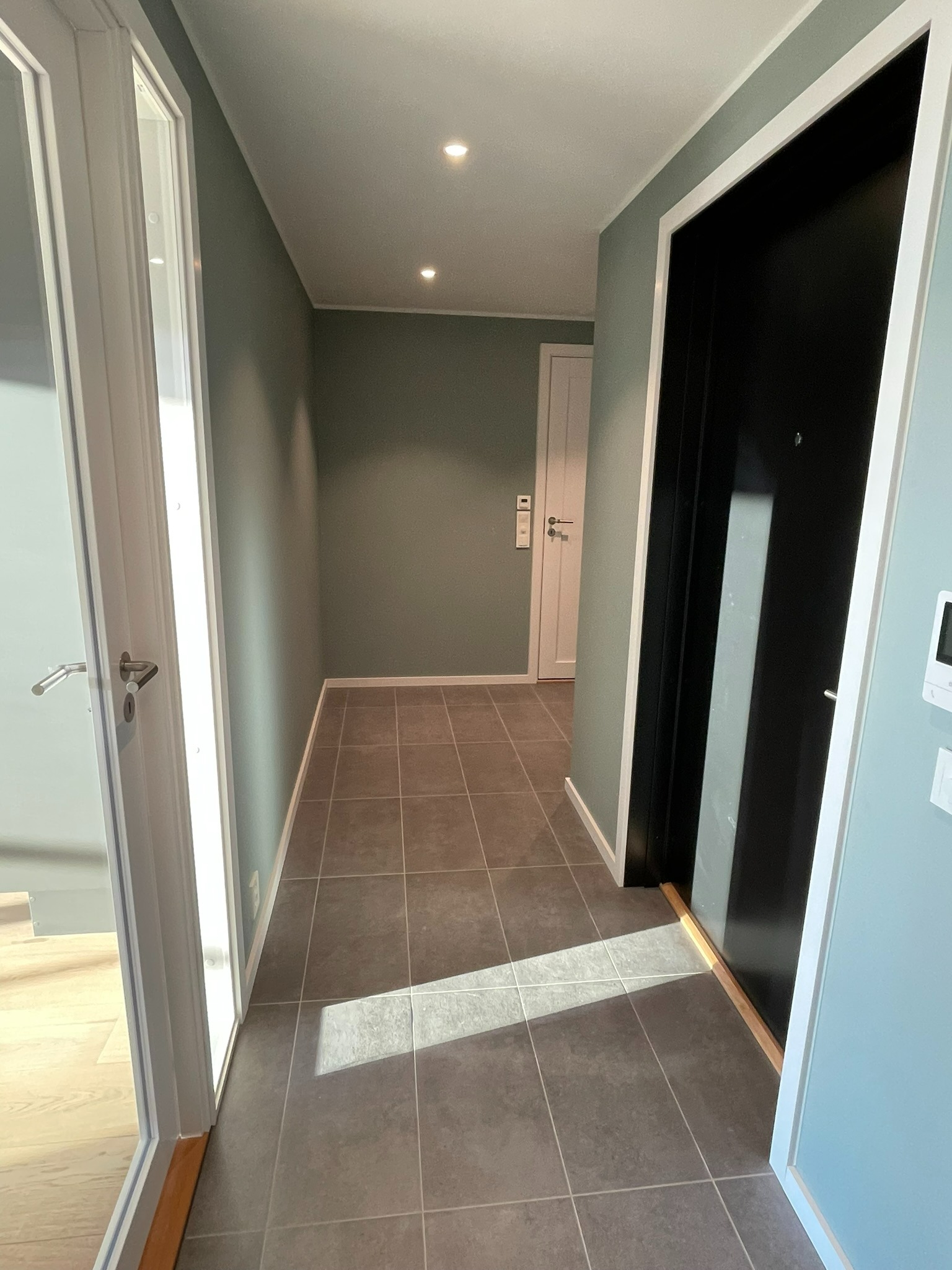 Romslig gang med fliser og gulvvarme.  Det blir montert skyvedørsgarderobe i innhuken foran badet ( ikke synlig på bildet) 