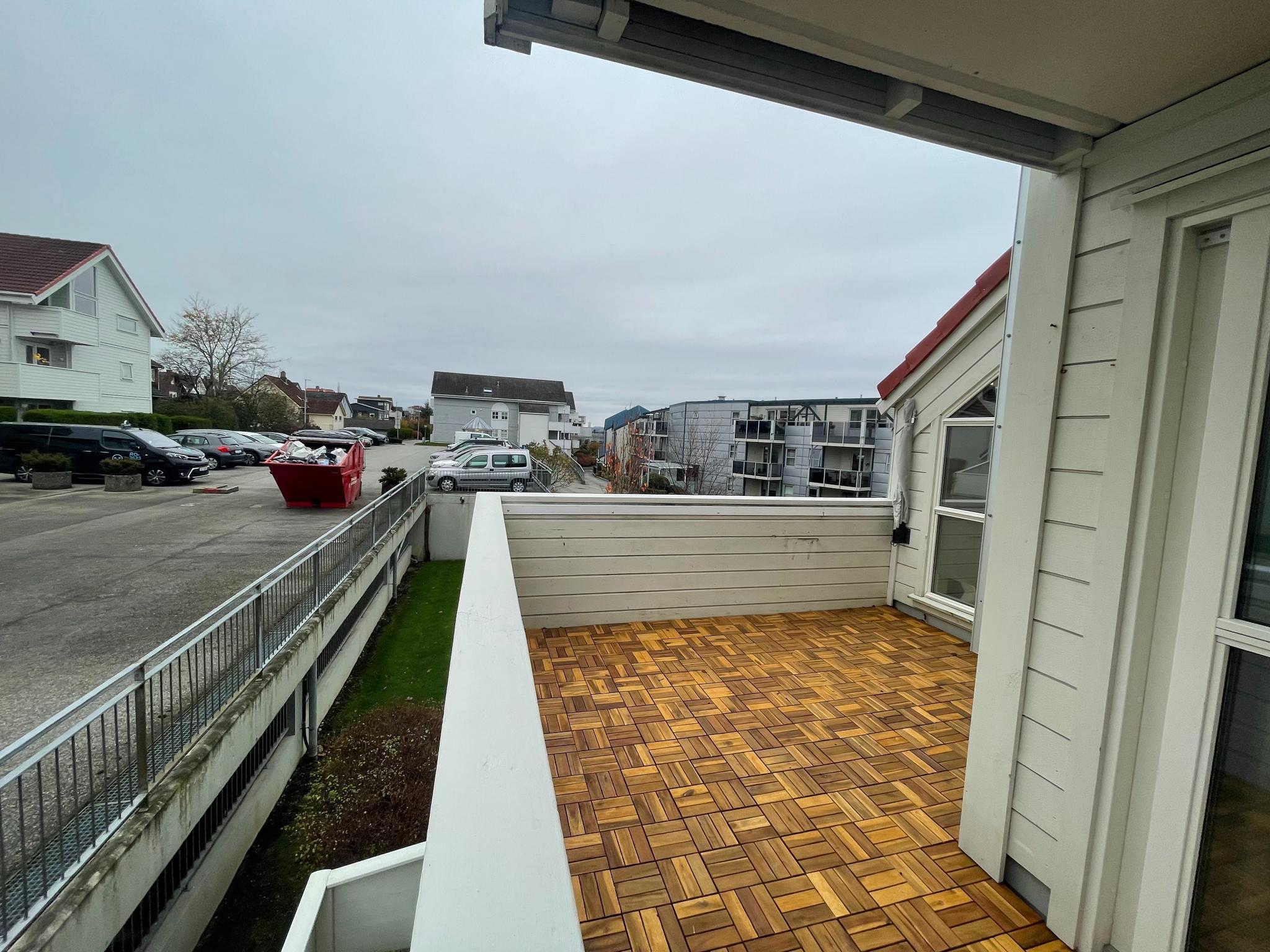 Balkong med kveldssol. Gjesteparkeringsområdet ligger svært nær leiligheten og er synlig fra balkongen.