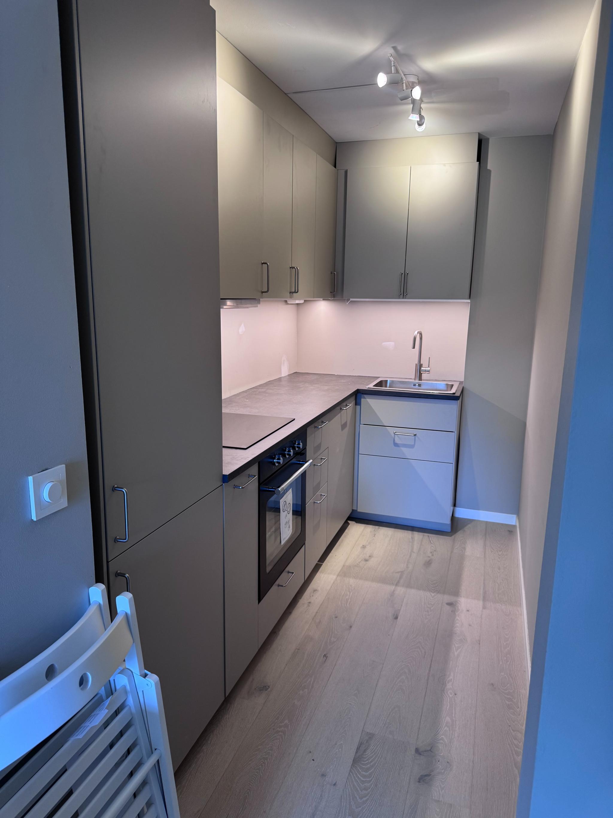 Kjøkkenet med full belysning og stoler til kjøkkenbordet.