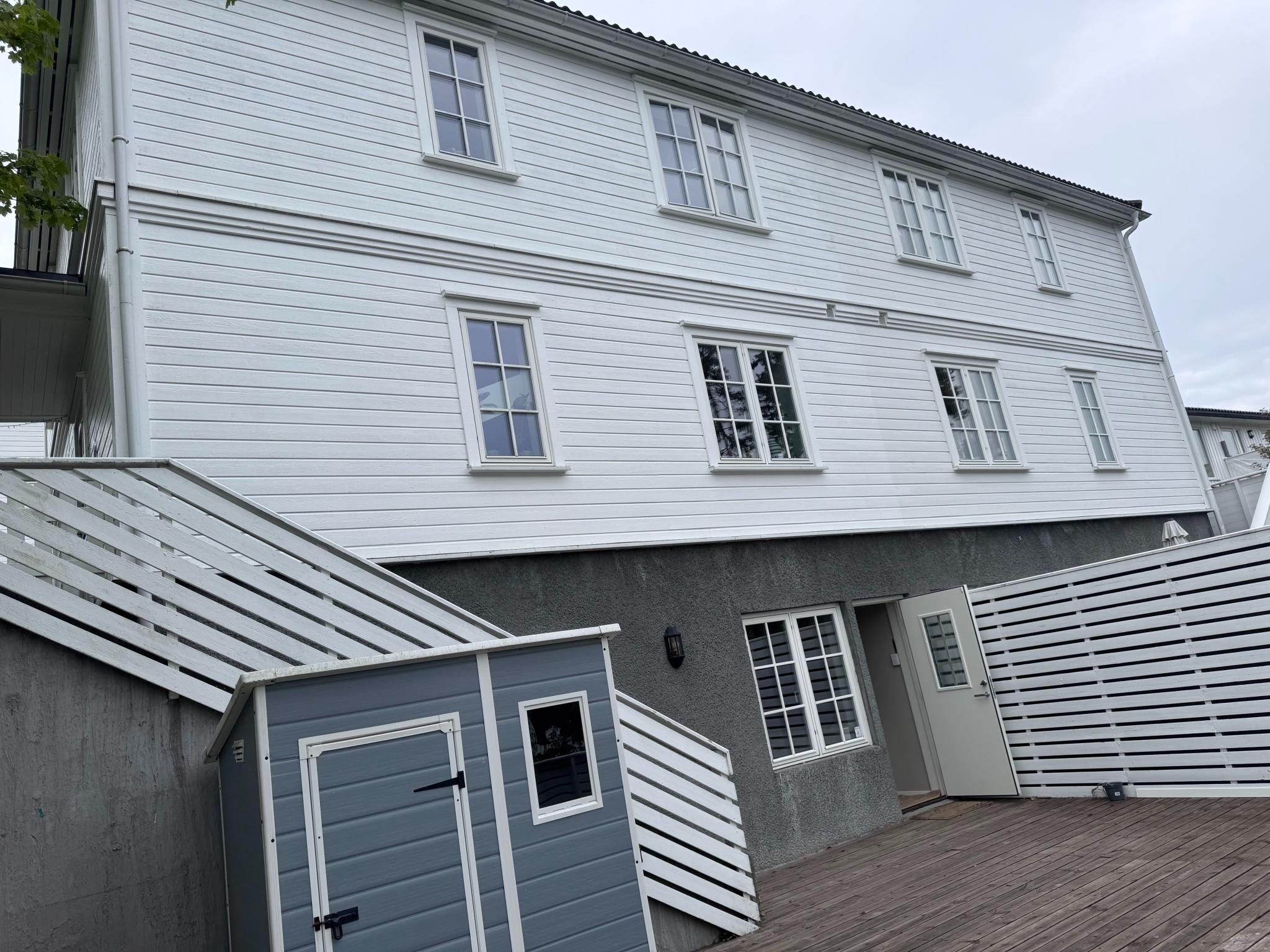 Fasadebilde av husets østside med stor terrasse og bod.