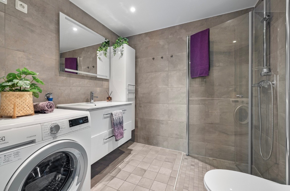 Delikat baderom med stilrene materialvalg og varme i gulv