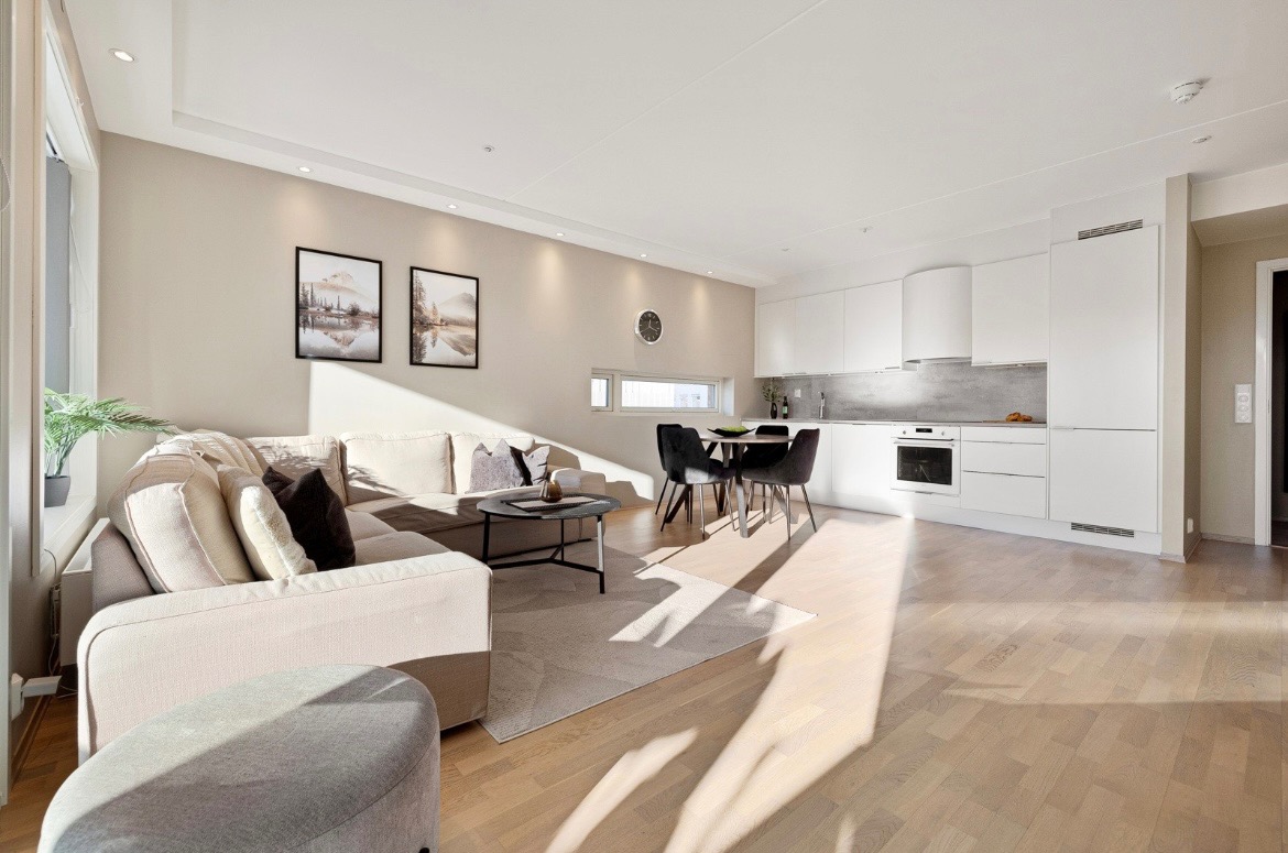 Allrommet med stue og spisestue har et stilrent kjøkken med alle hvitevarer inkludert