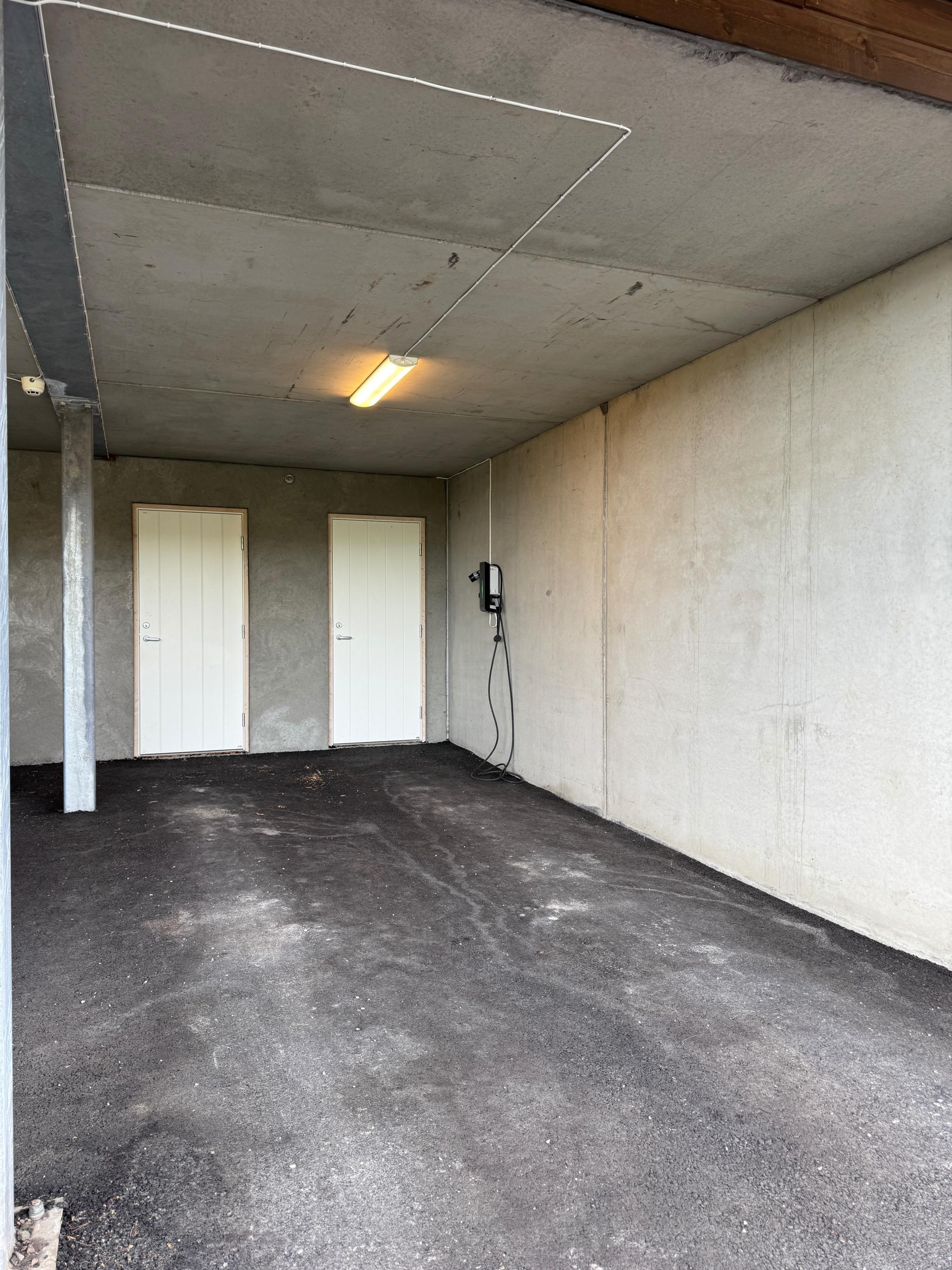 Carport med elbil lader og bod.
