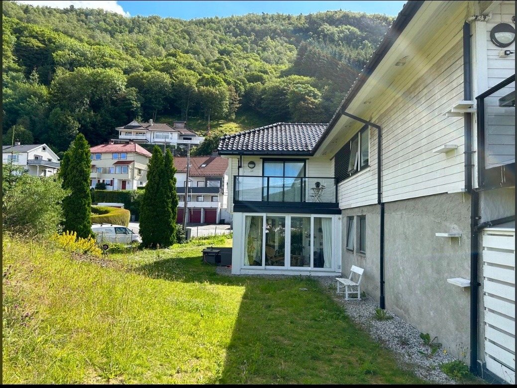 Hage på fremsiden. Ser leilighetes tilhørende balkong i 2. etg