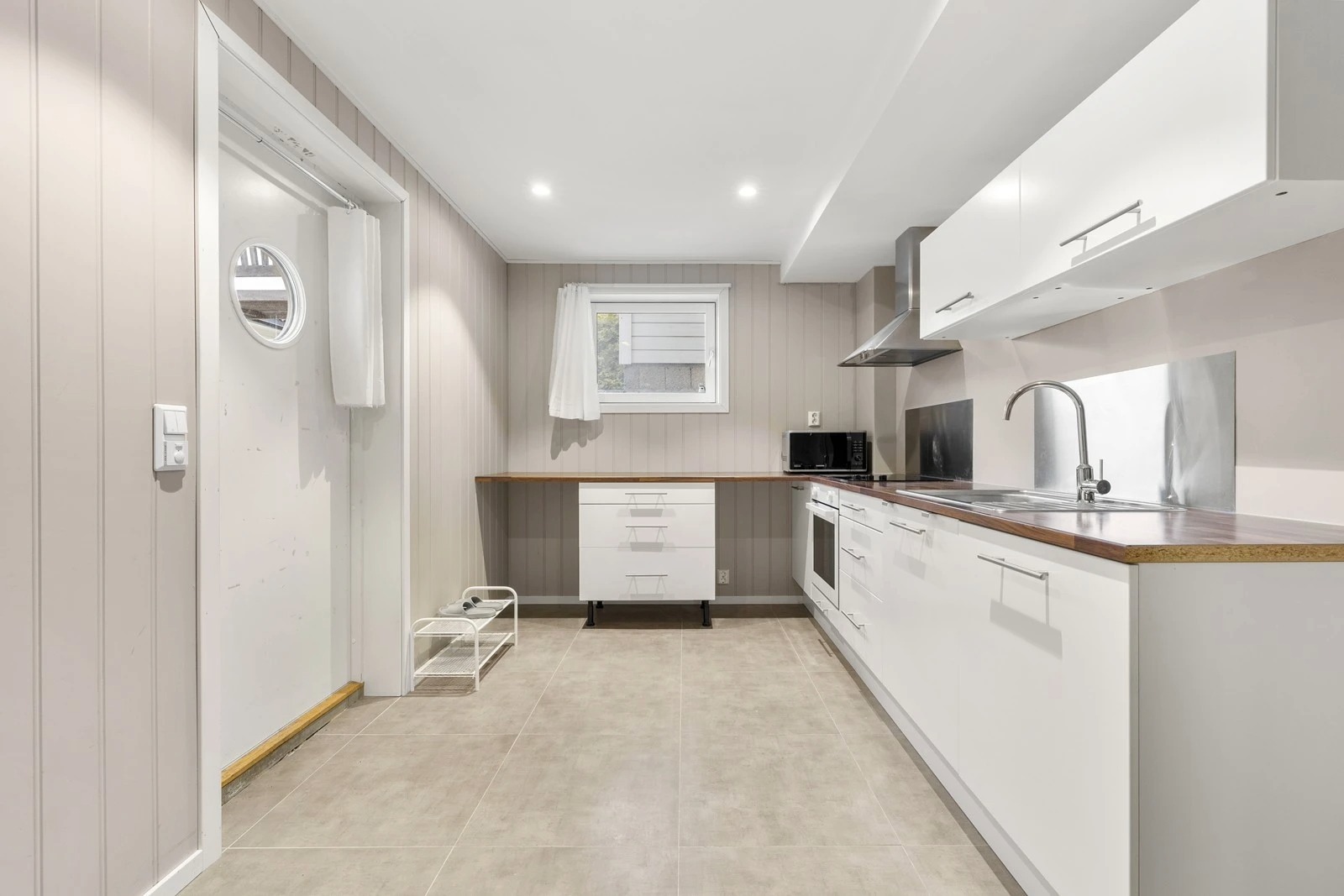 Kjøkkeninnredningen er klassisk og hvit med laminat benkeplate og frittstående hvitevarer.