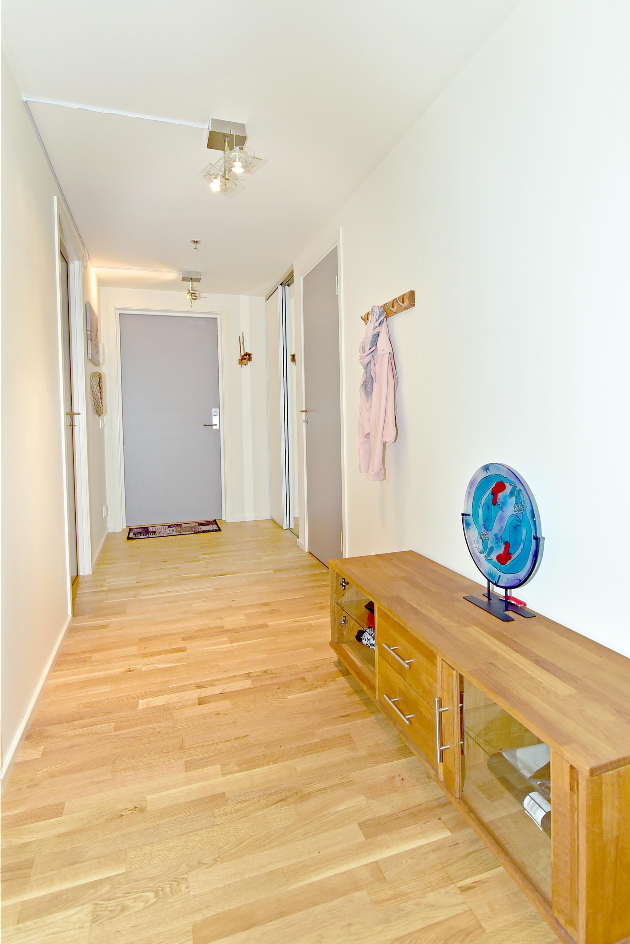 Innendørs gang med skyvedørsgarderobe og tilgang til tre soverom og innendørs bod. Innendørs bod har fryser og hyllesystem