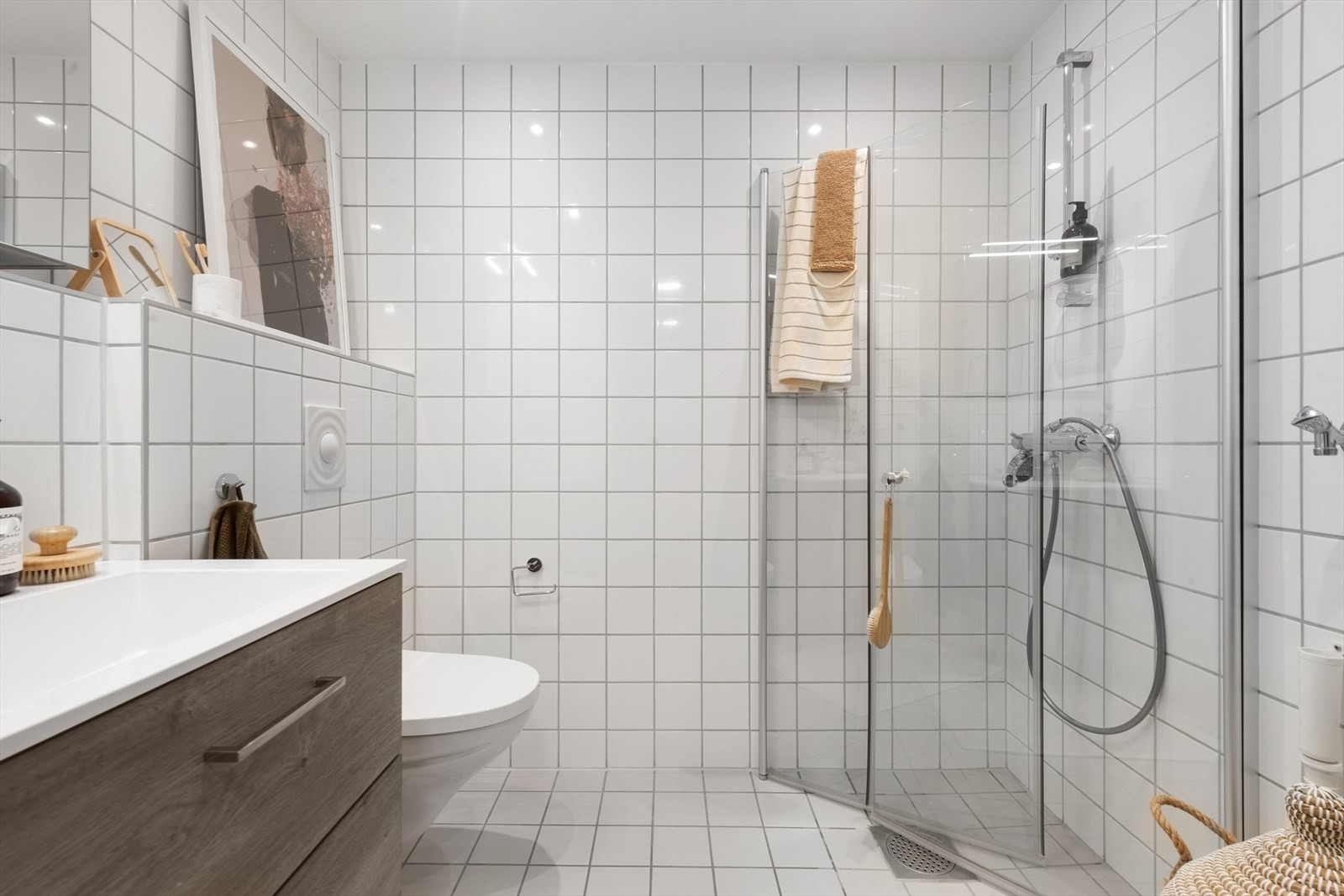 Lyst flislagt bad, med veggmontert toalett og helt ny kombinert vaskemaskin og tørketrommel. 