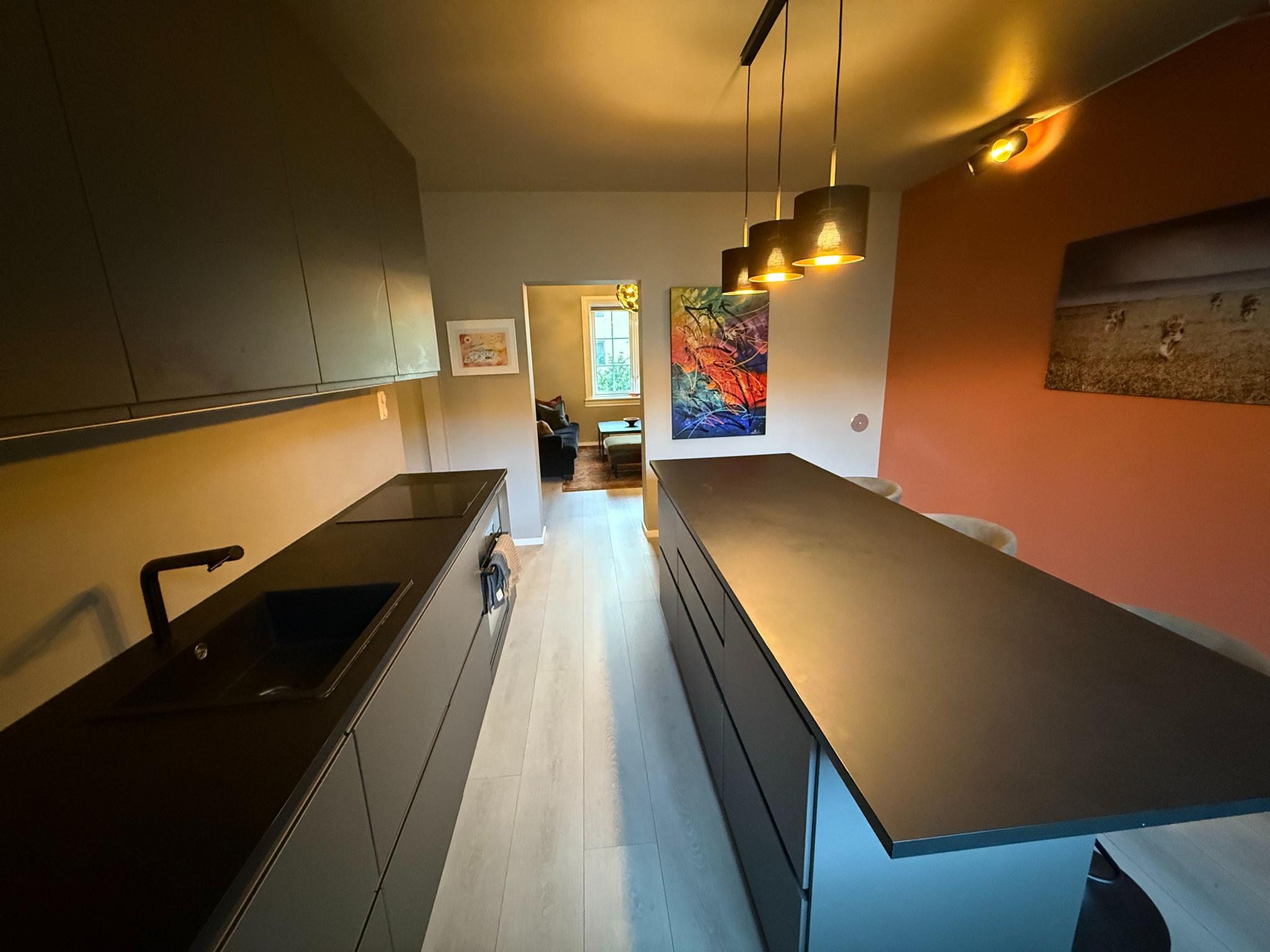 Kjøkken med god skapplass, integrerte hvitevarer og en stor kjøkkenøy for inntil 8 persone