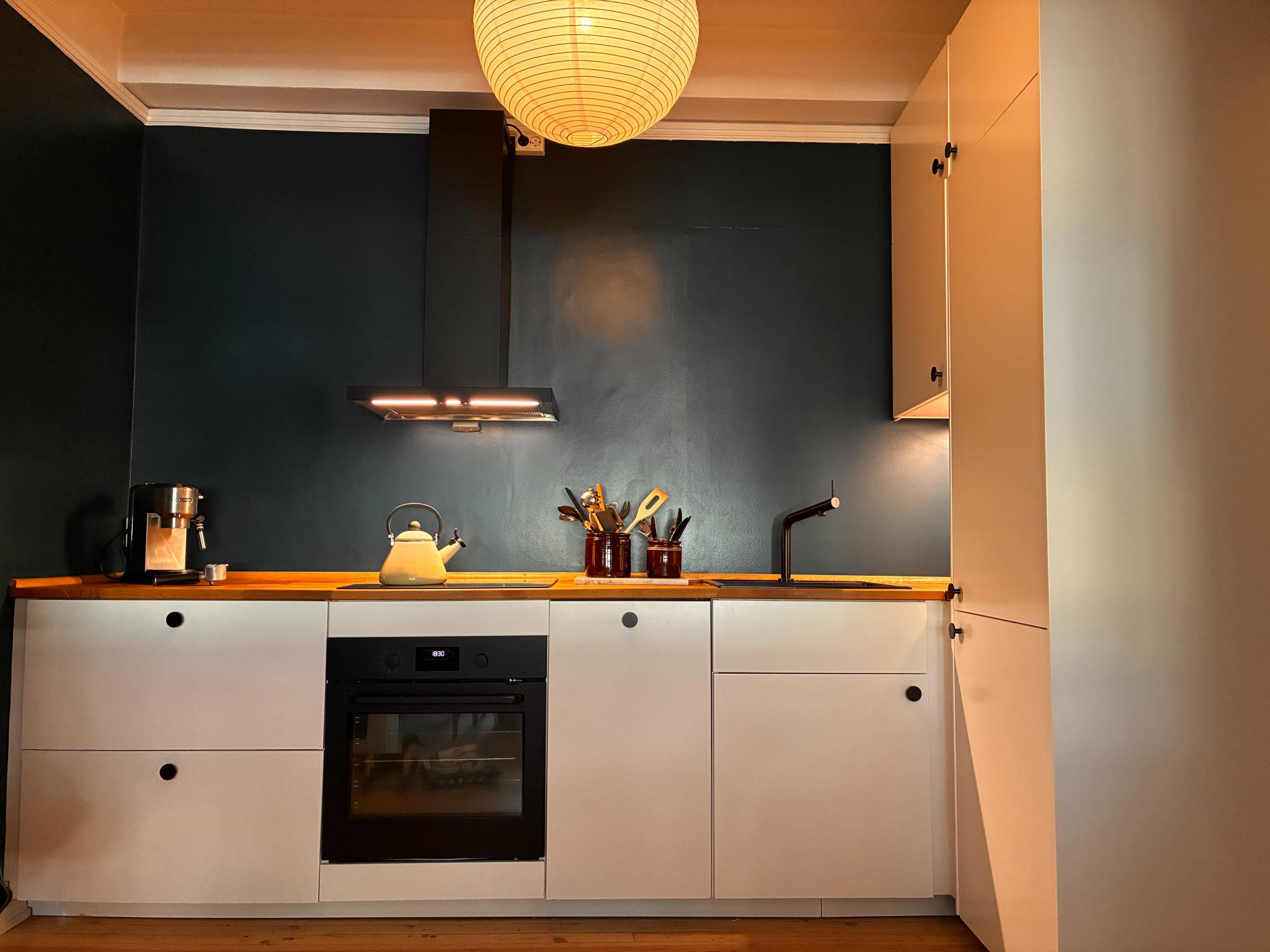 Åpen kjøkkenløsning inn til stue, med komfyr, oppvaskmaskin, kjøl og frys