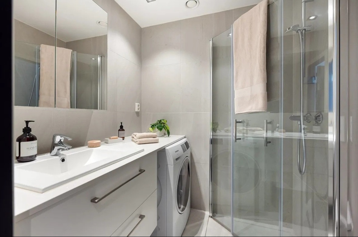 Oppbevaring bak speil og under vask. Toalettet har vask, dusj, vaskemaskin og toalett. 