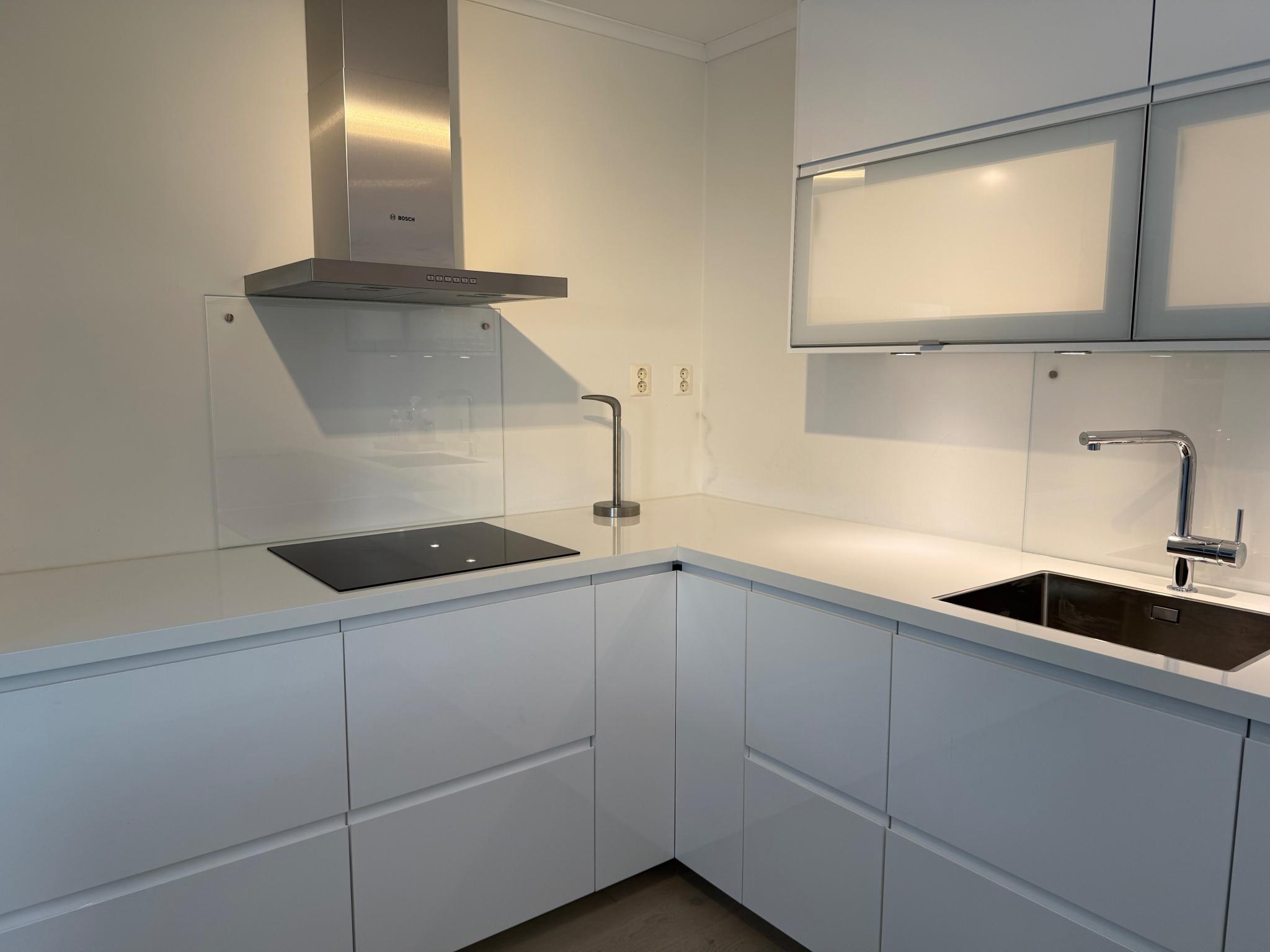 Lekkert høyglanset hvitt kjøkken med mye oppbevaring. 