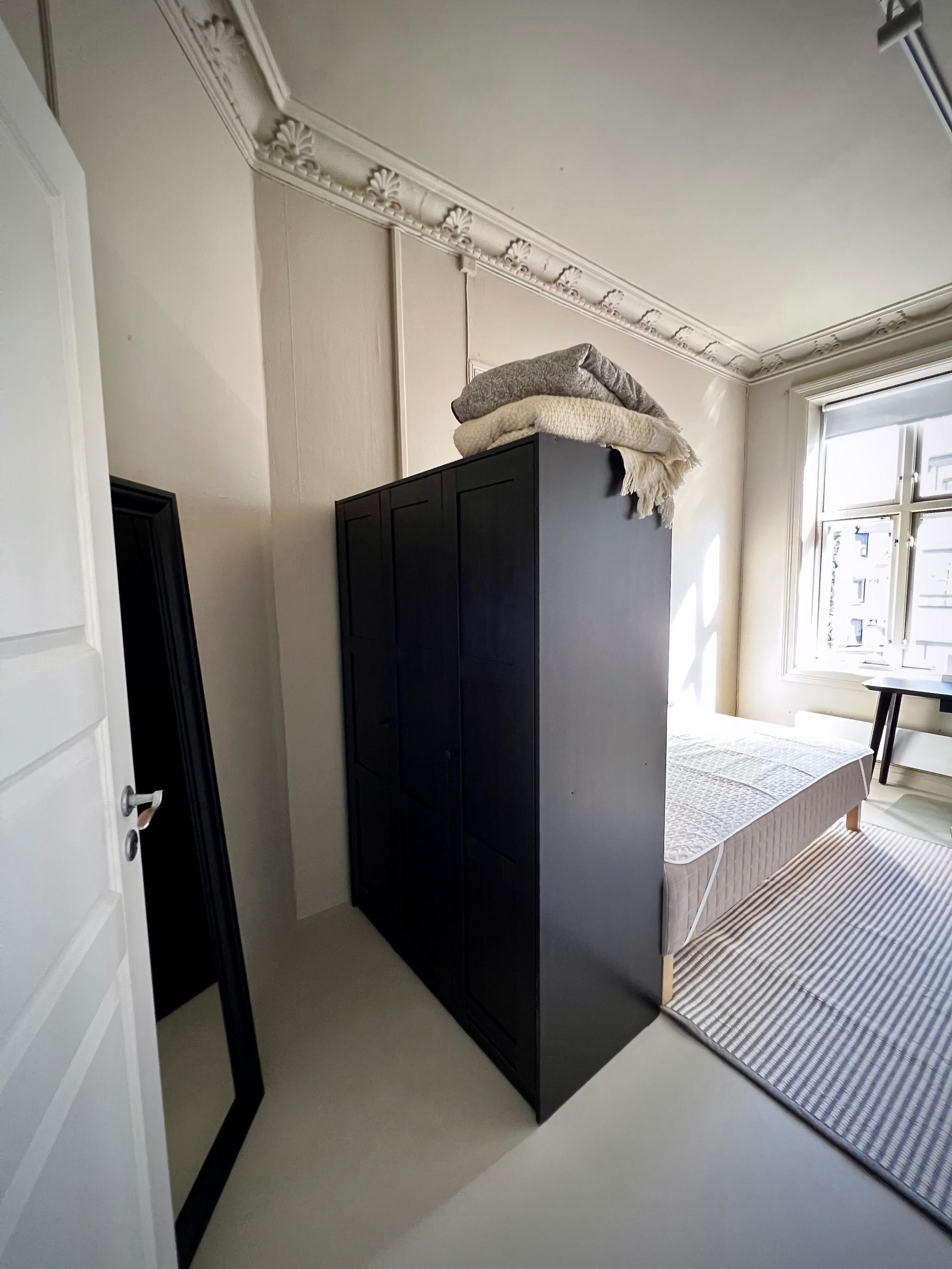 Soverom 9,5m2 inneholder 120 seng, garderobeskap med heng og hyller, arbeidsbord med stol, speil, teppe og lamper.