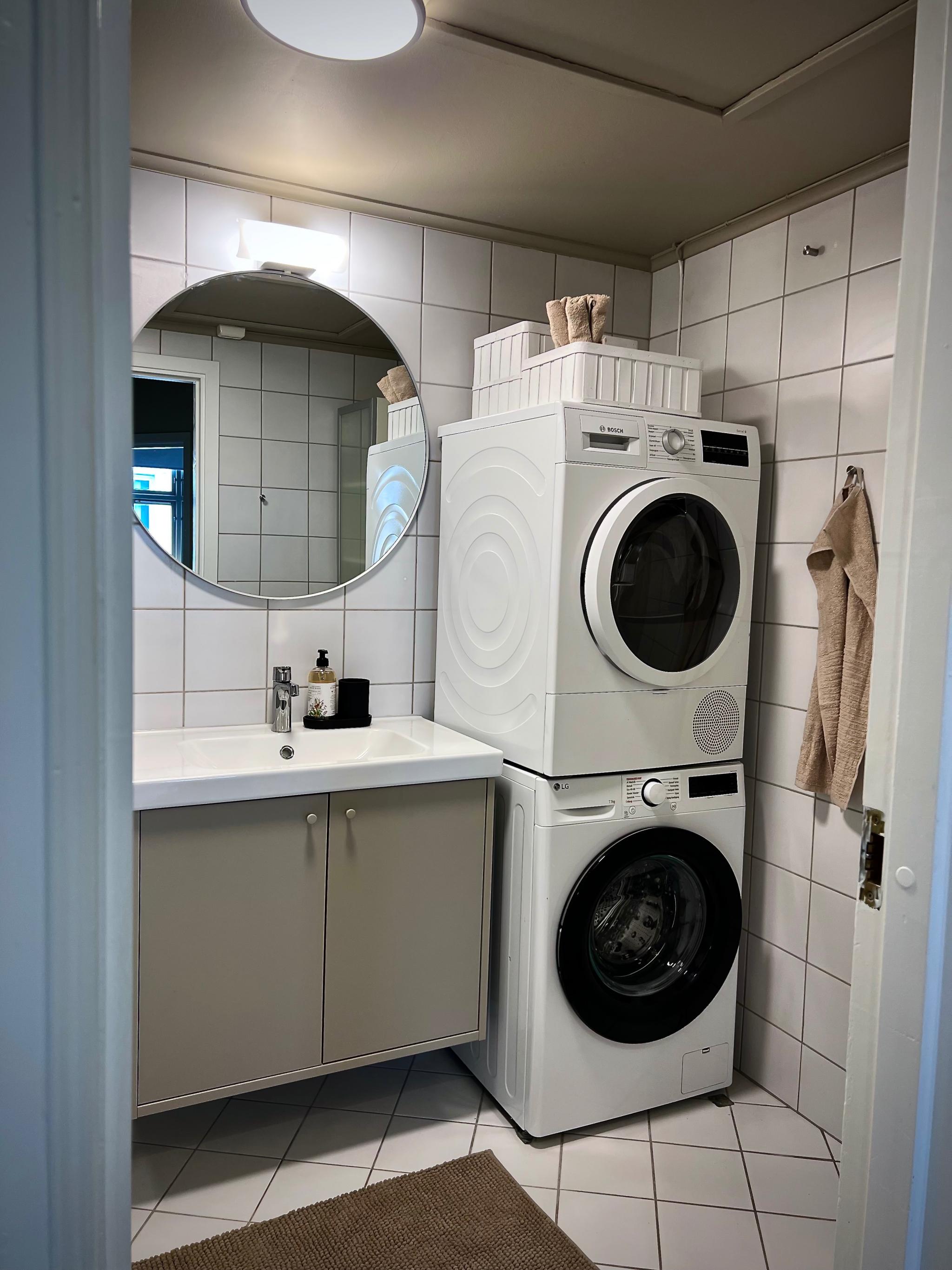 Bad med dusjkabinett, vaskemaskin og tørketrommel.
