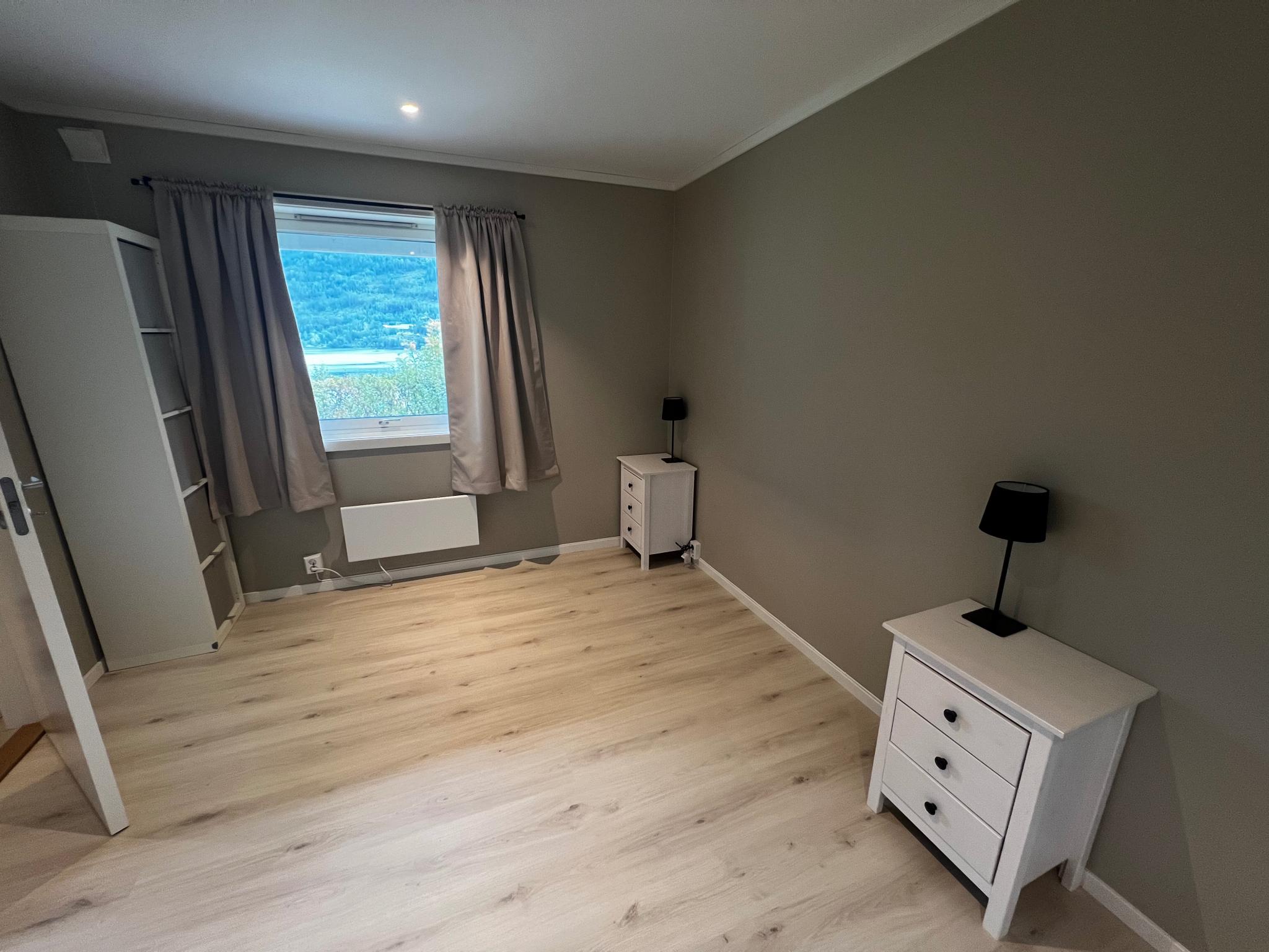 Soverommet inkluderer to nattbord, to garderobeskap, en kommode og en hylle. 